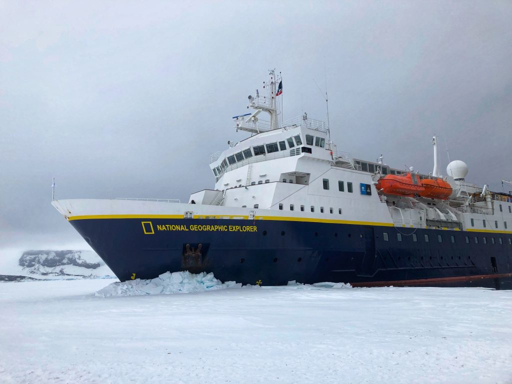 National Geographic Explorer ship parked in Antarctic sea ice near James Ross Island under overcast skies.