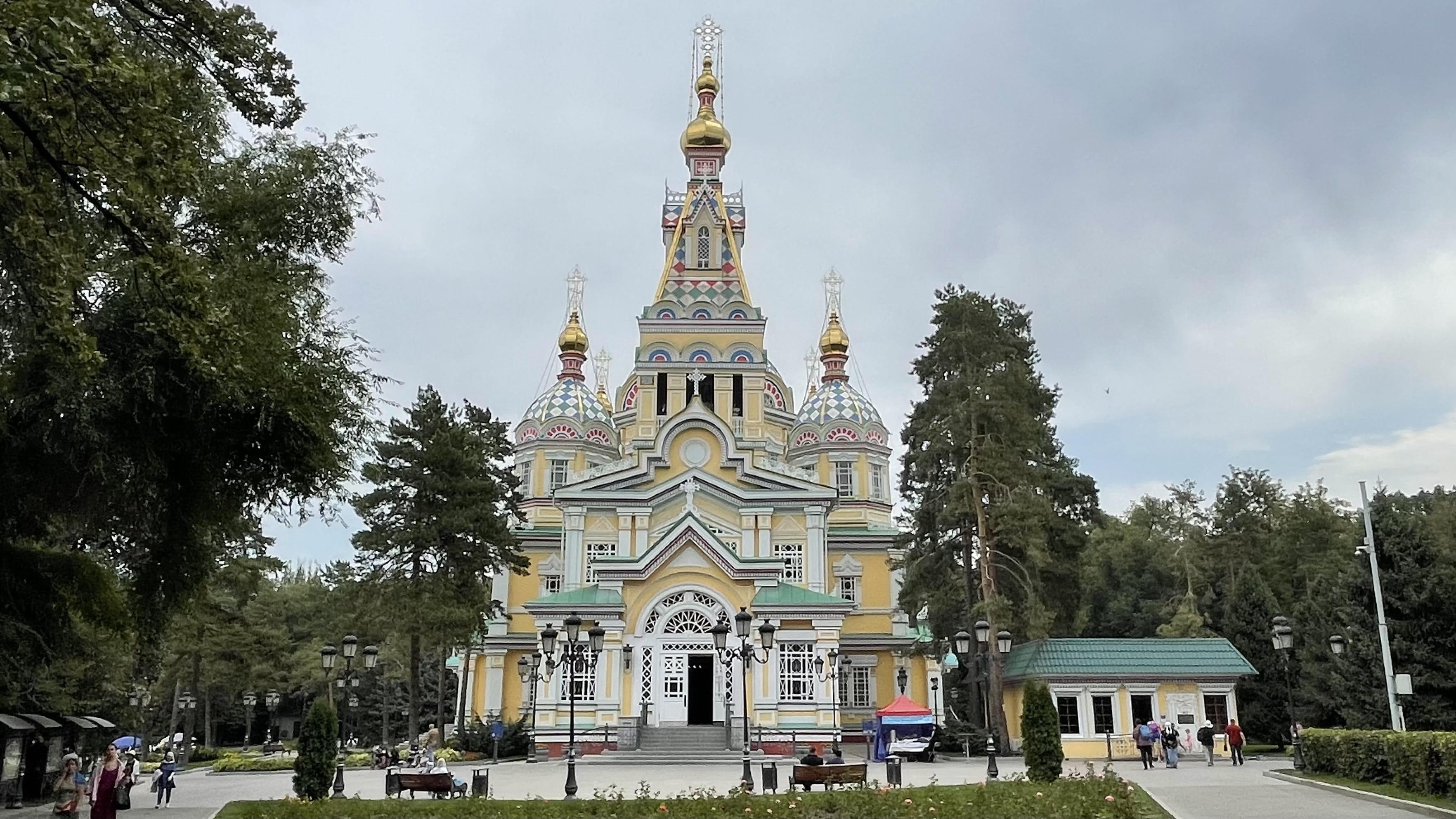 Zenkov Cathedral in Panfilov Park, Almaty, a colorful Russian Orthodox church with ornate domes surrounded by trees and walking paths
