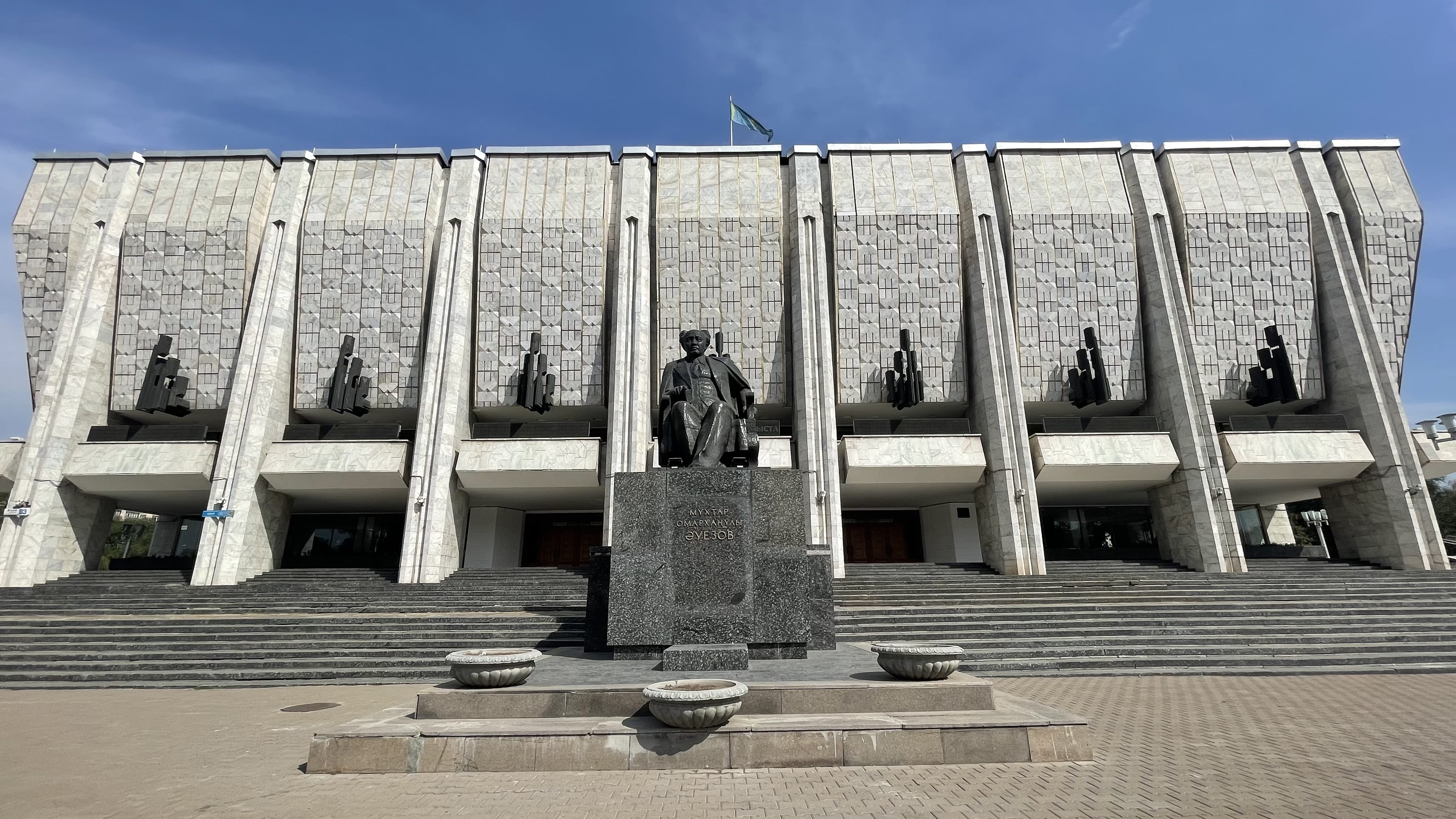 Kazakh Academic Drama Theatre in Almaty, a Soviet-era Brutalist building with a statue of Mukhtar Auezov standing in front of its monumental façade