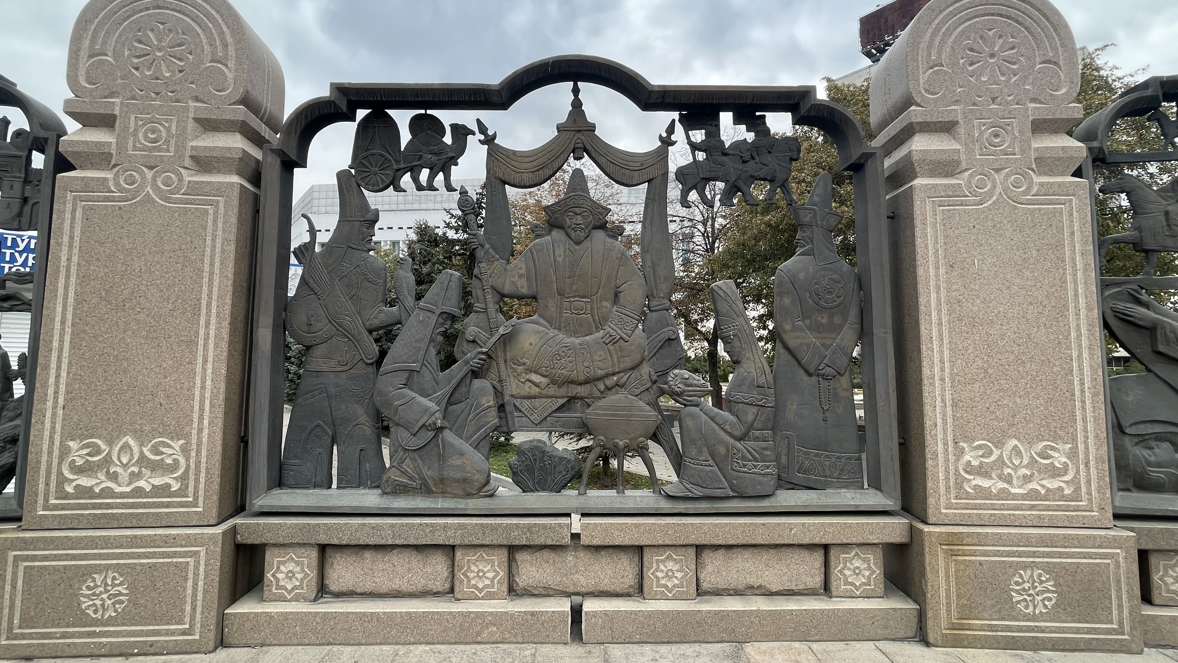 Soviet-era monumental relief sculpture in Almaty depicting Kazakh historical figures framed by carved stone panels
