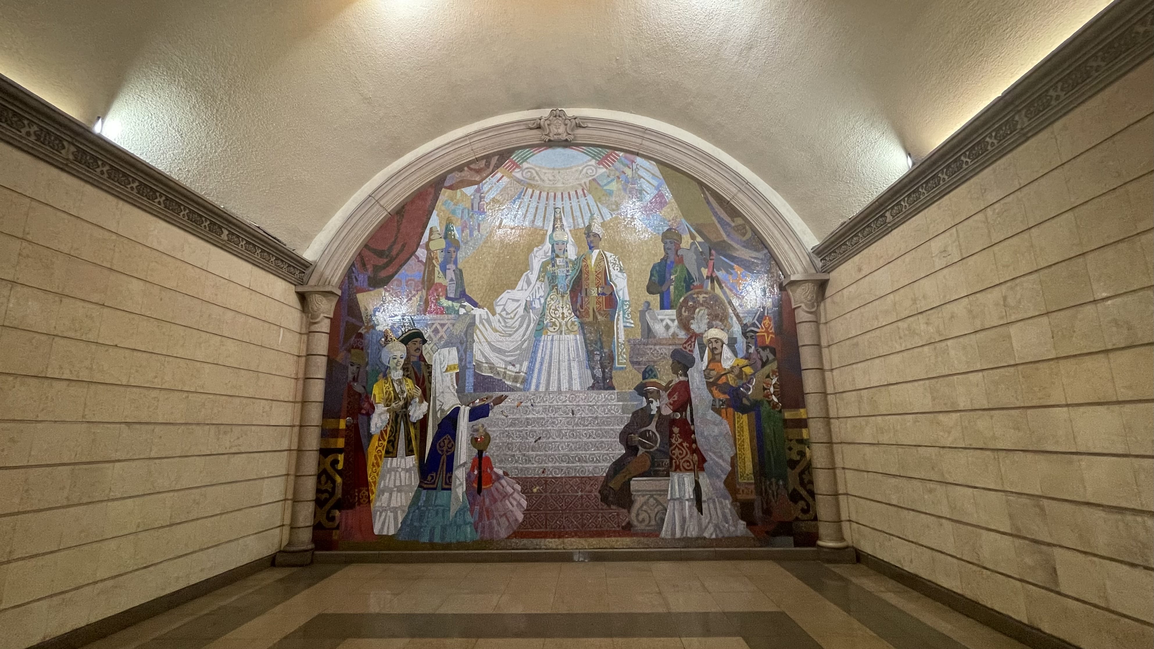 Colorful Soviet-era mosaic depicting figures in traditional dress inside an Almaty metro station, seen during a 2 days in Almaty visit.