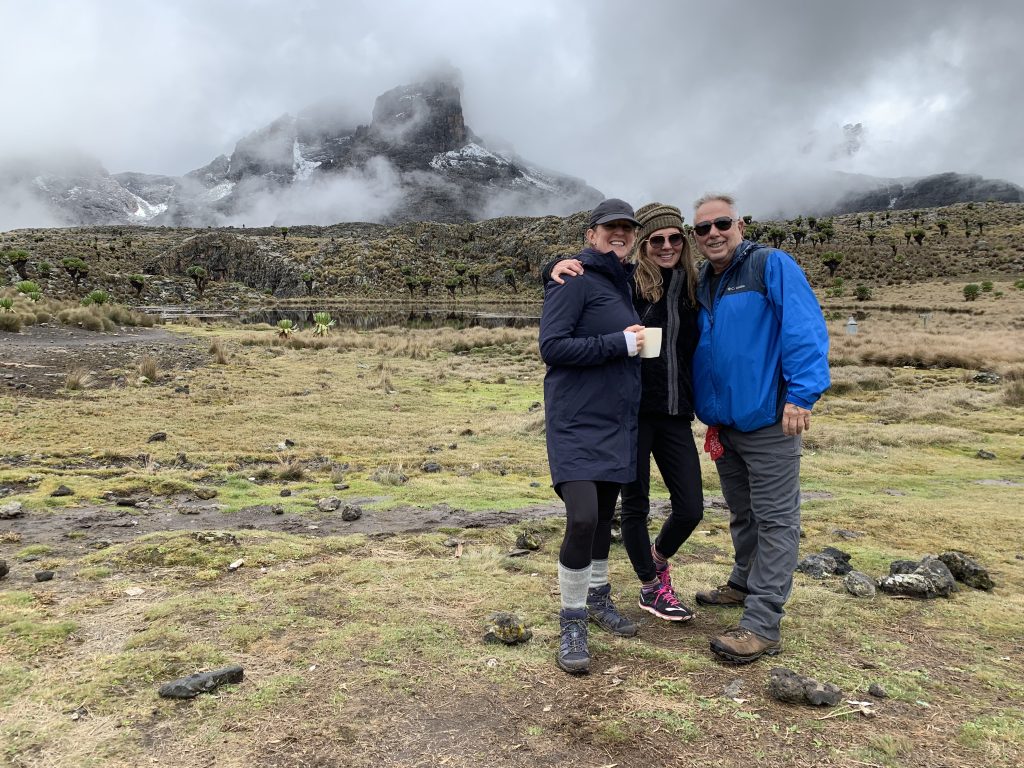 Mount Kenya hikers at Mintos Camp with misty peaks in the background.