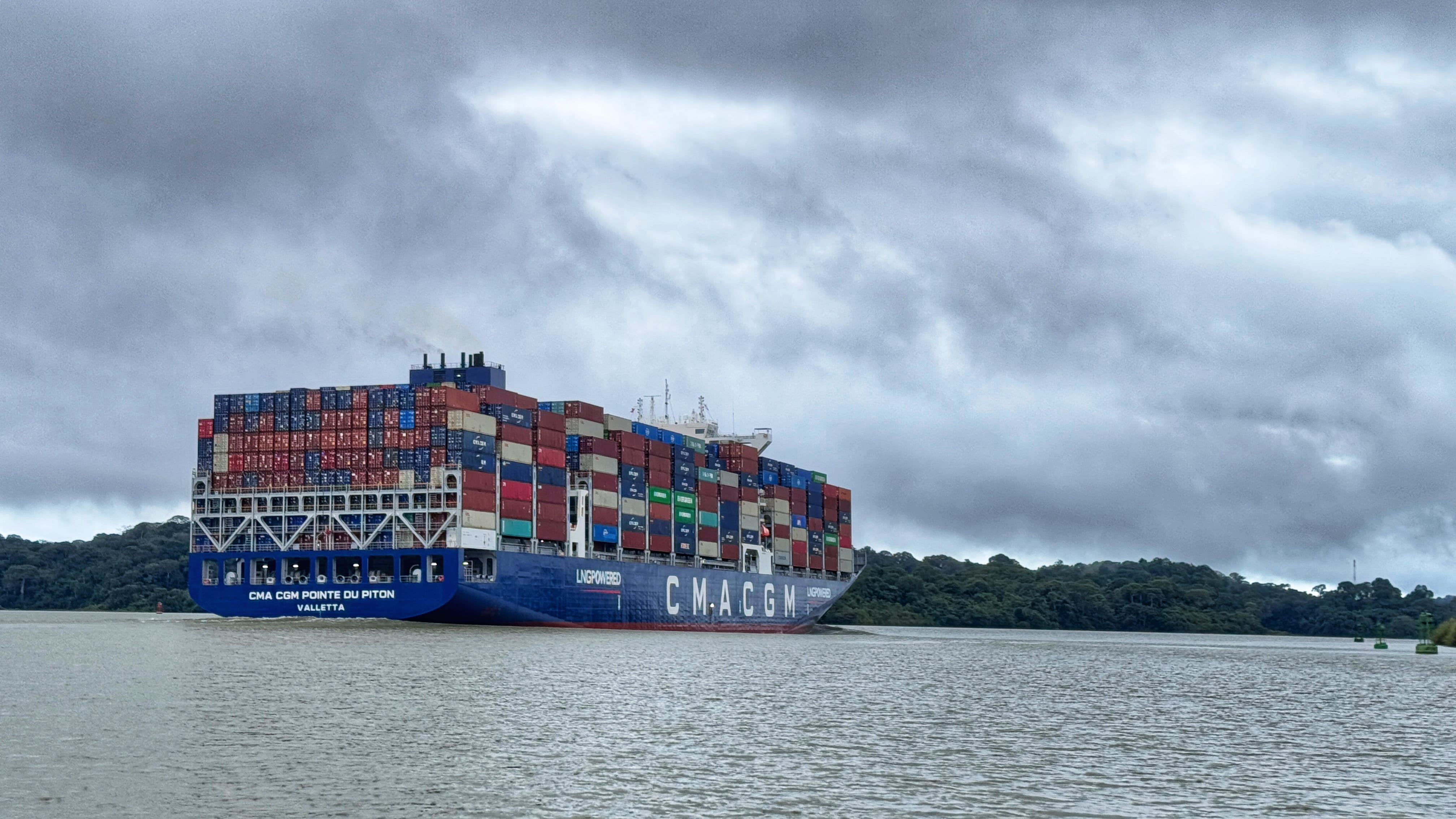 Massive CMA CGM container ship passing through the Panama Canal under cloudy skies during 4 days in Panama City.