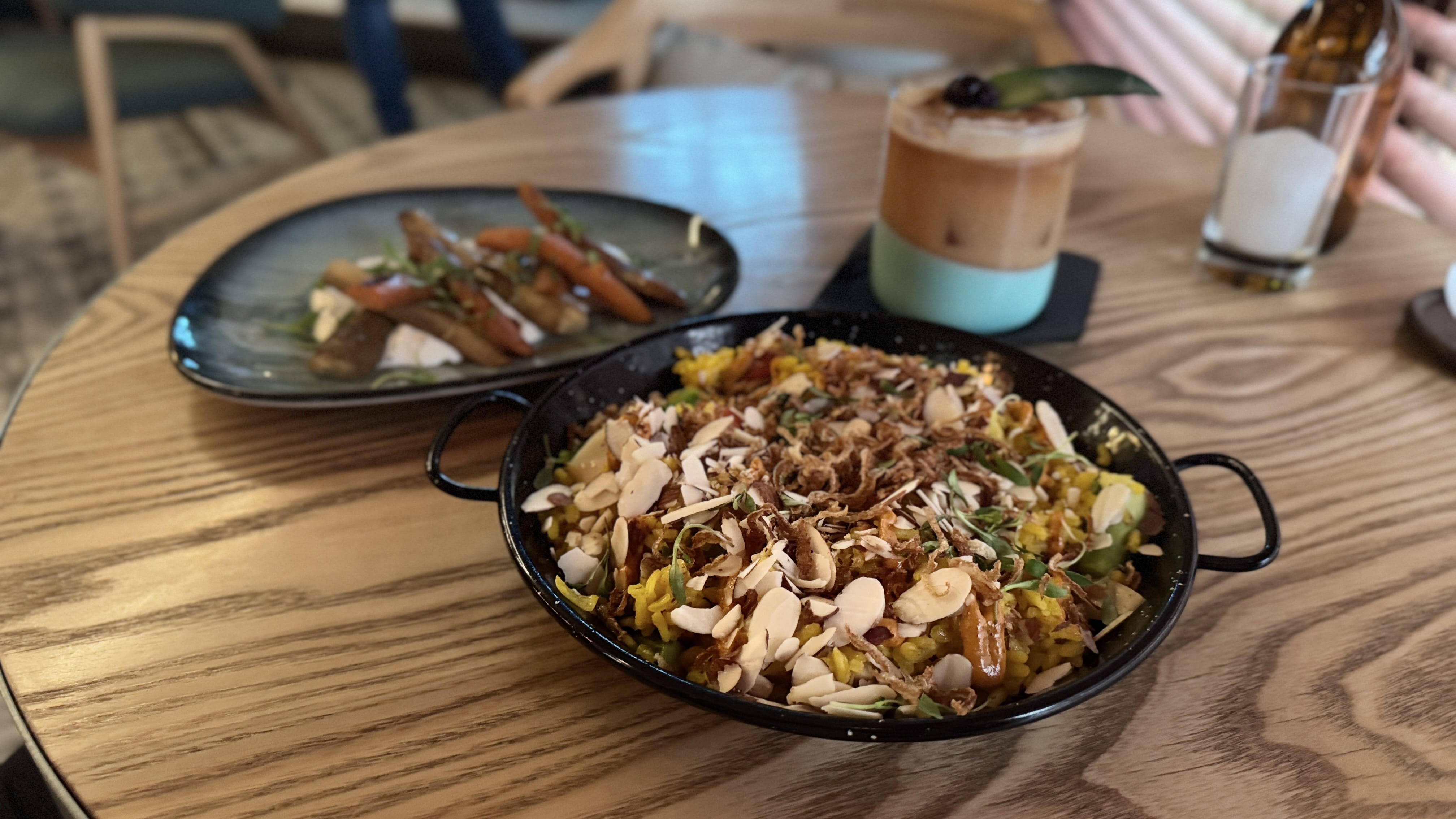 A plate of vegetarian jackfruit paella topped with almonds and herbs, served alongside roasted carrots at Mahalo Cocina y Jardín in Panama City.