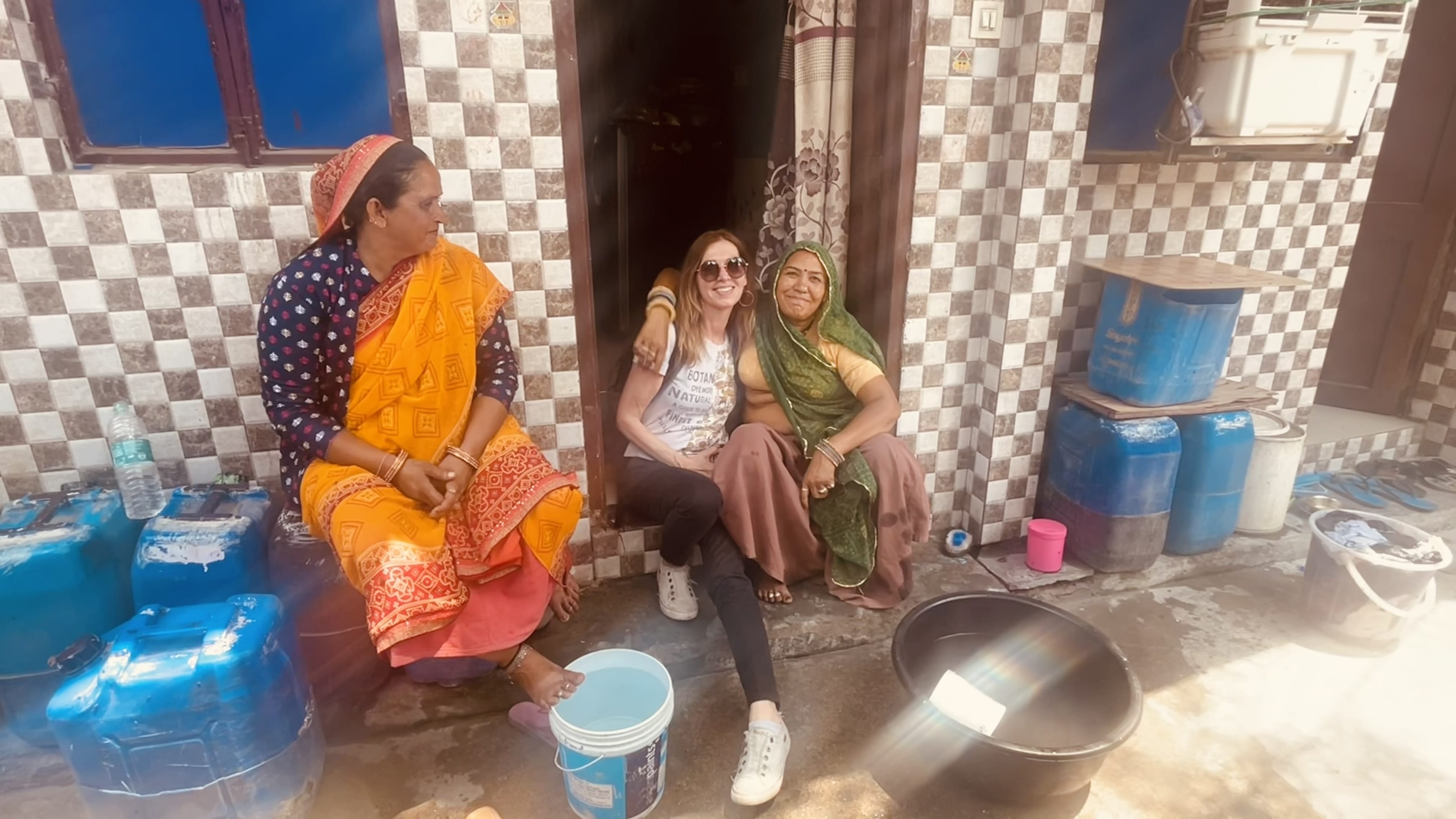 A visitor sits with two women outside a tiled home in Kasumpur, a residential neighborhood in Delhi, India.