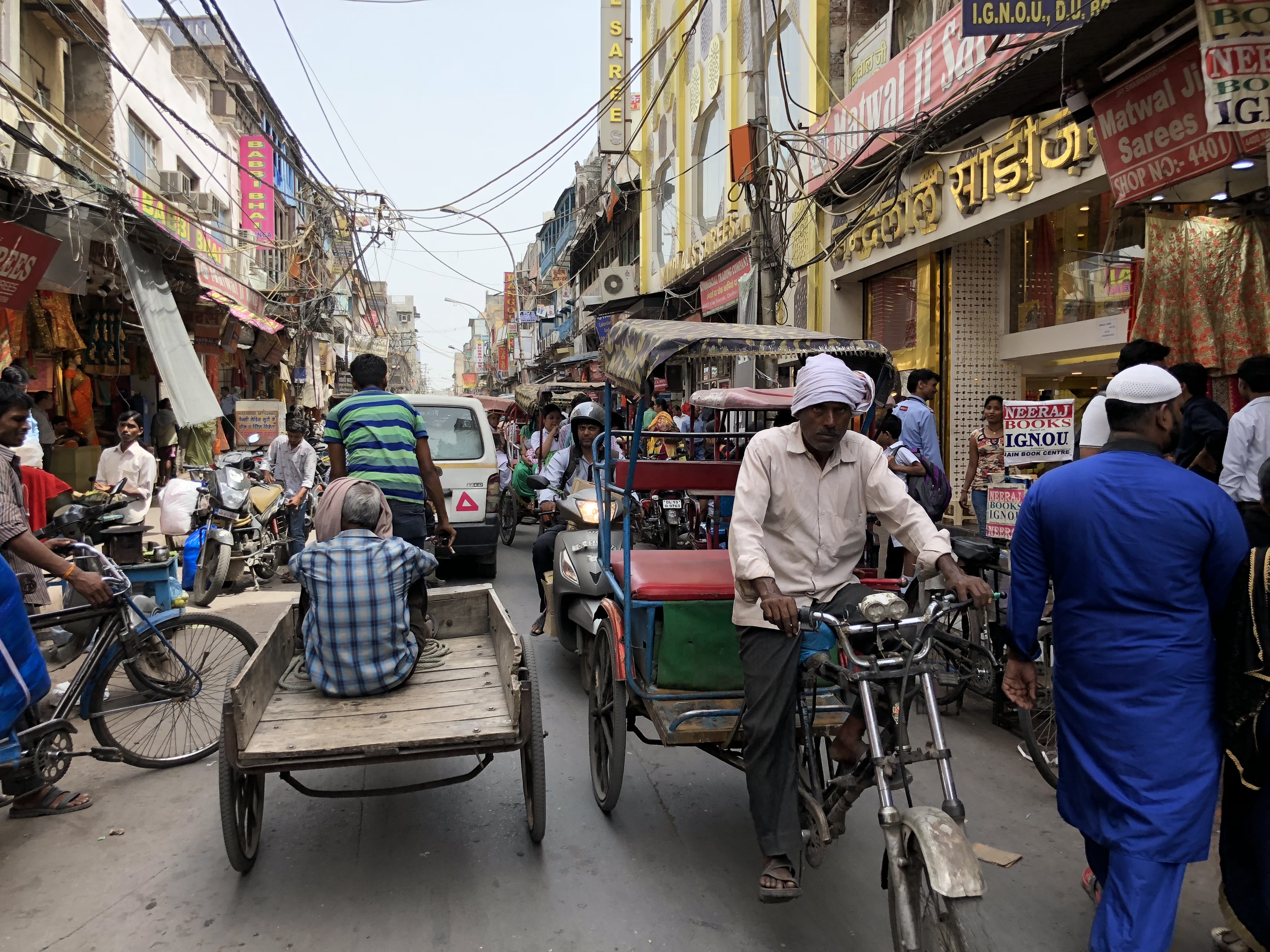Crowded street in Chandni Chowk, Old Delhi, with rickshaws, shops, and pedestrians