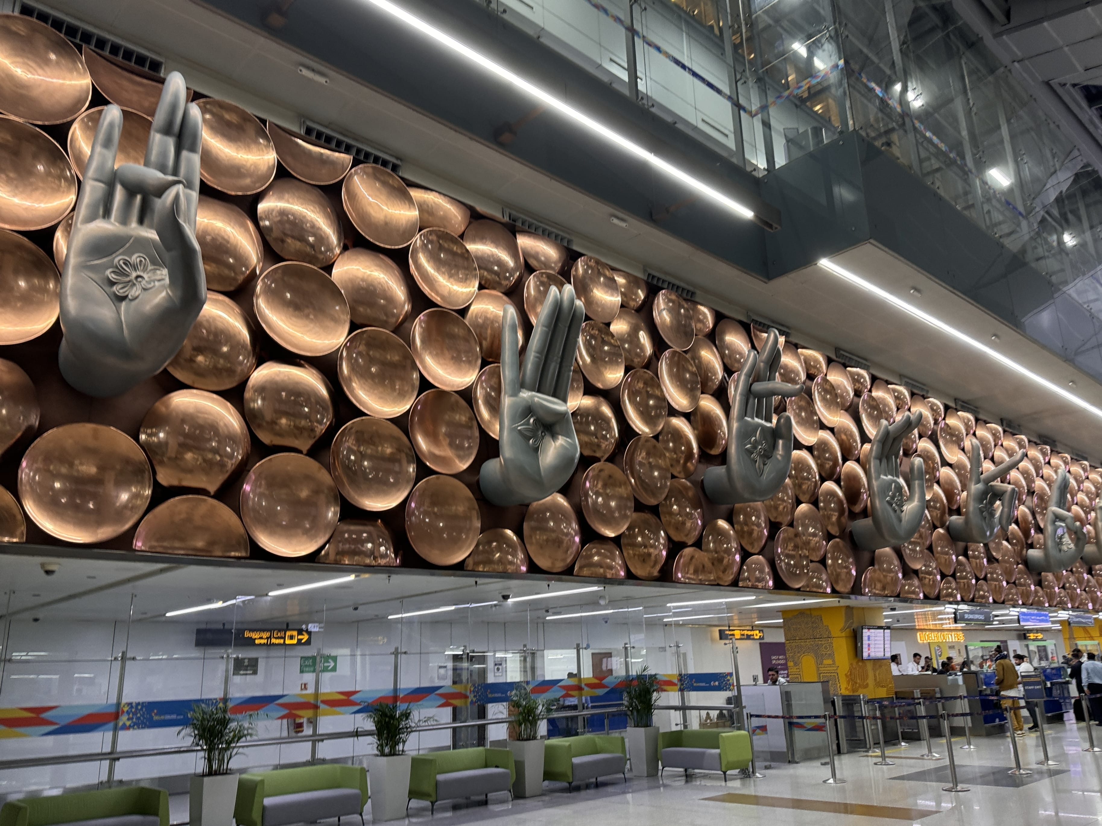 Large installation of symbolic mudra hand gestures on a metallic backdrop at Indira Gandhi International Airport in Delhi, India.