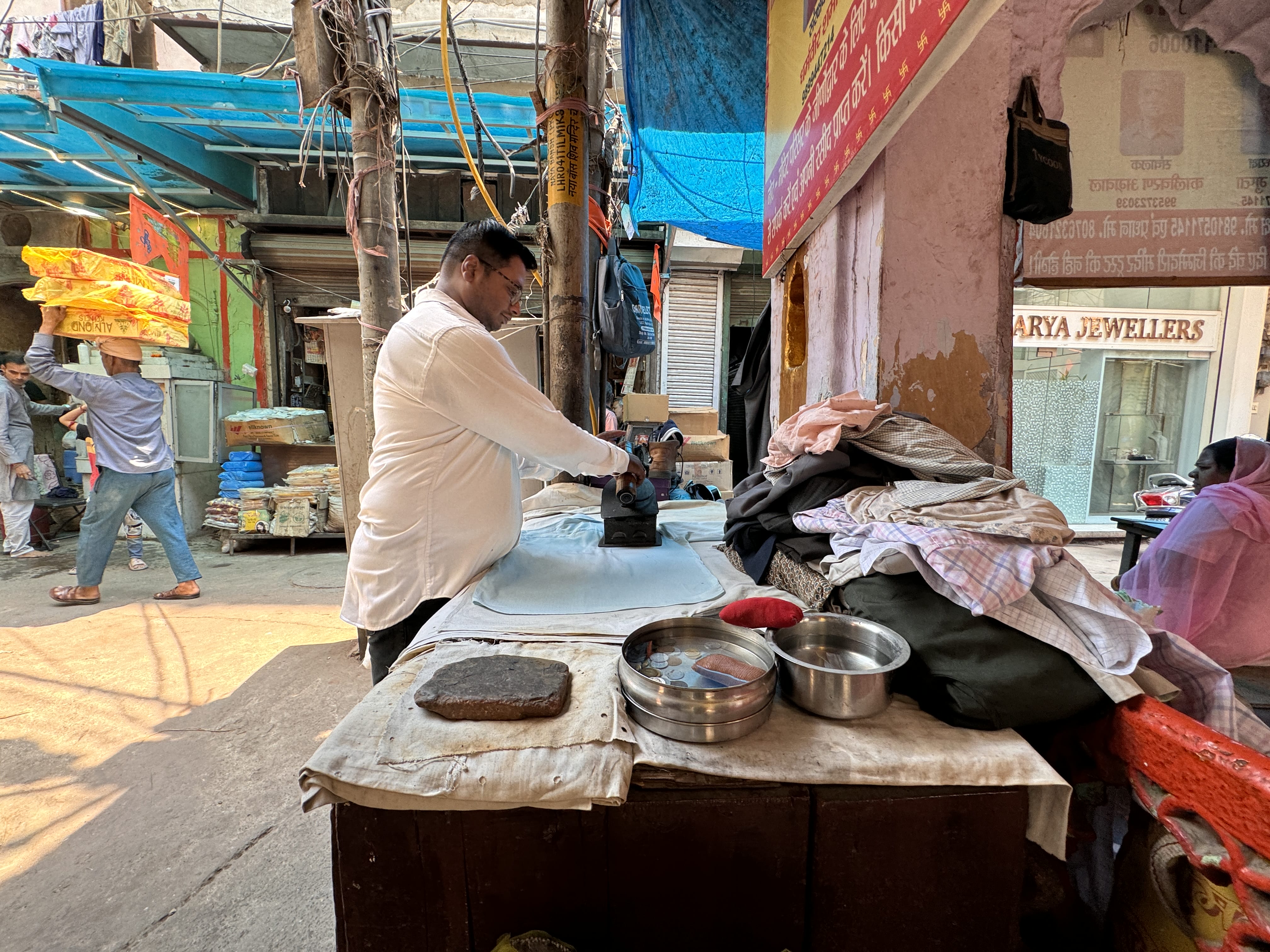 Man ironing clothes with a traditional coal-heated iron in Old Delhi