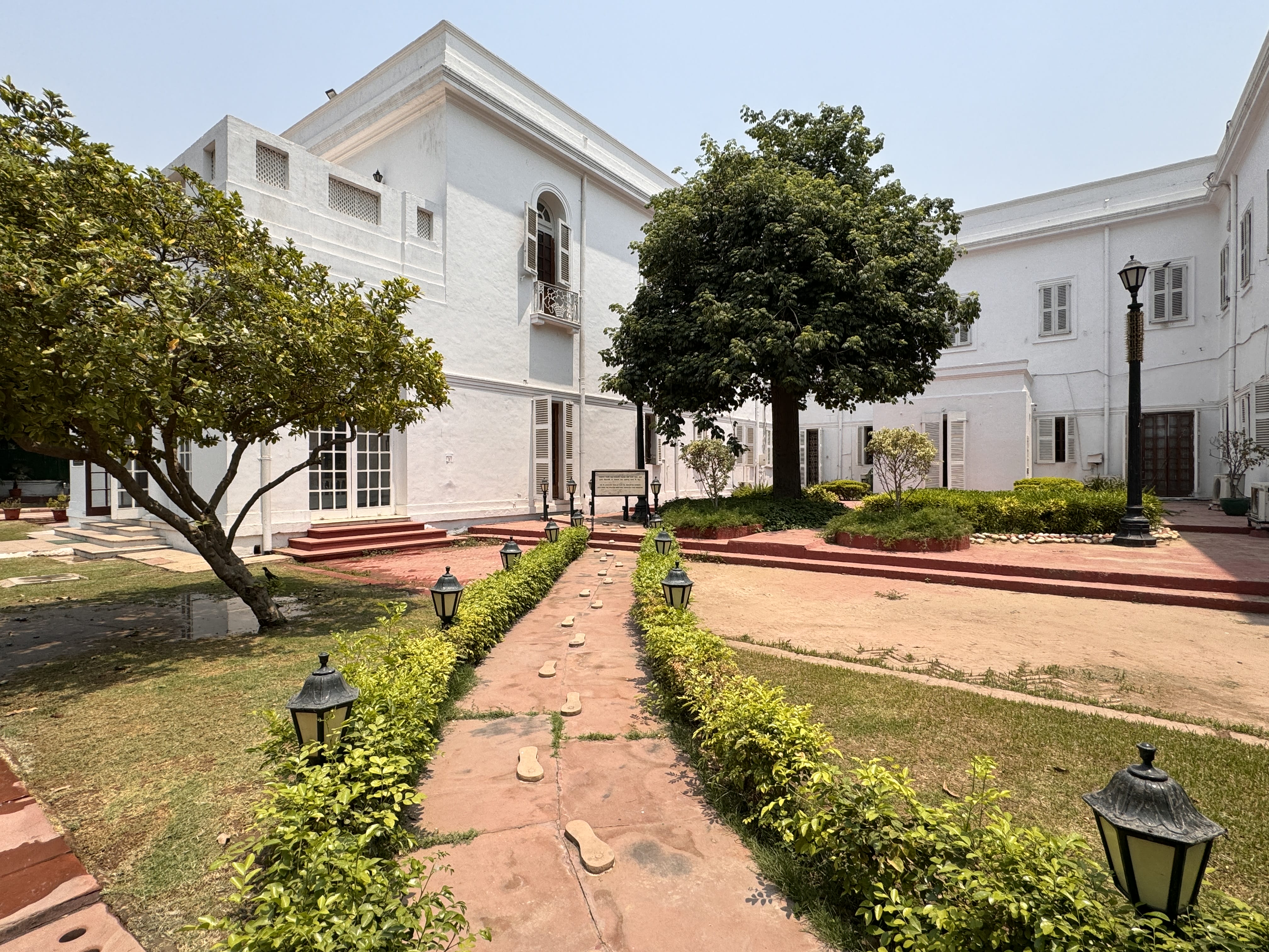 Exterior view of Gandhi Smriti museum in Delhi with a garden path marked by sculpted sandals