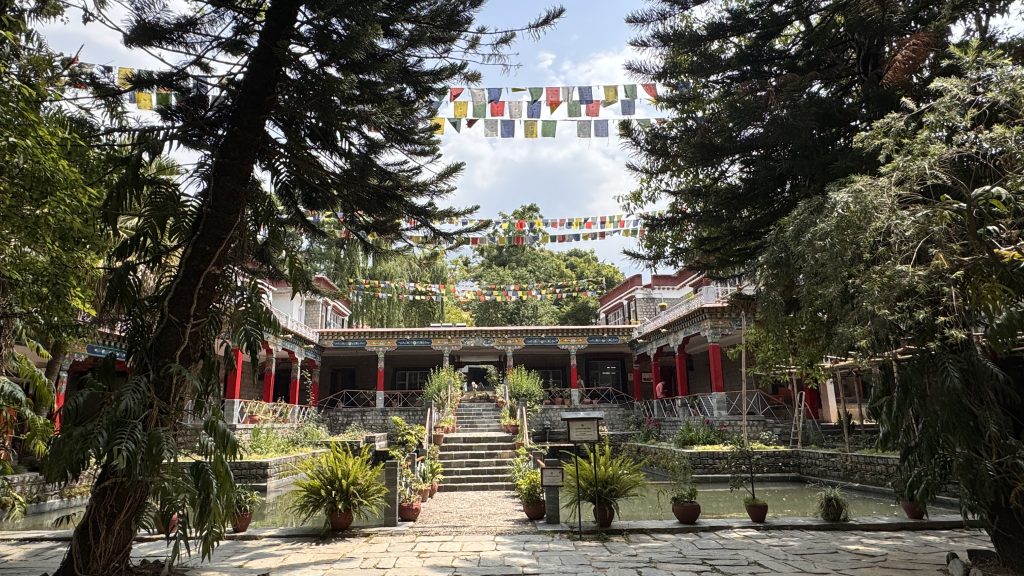 Peaceful courtyard at Norbulingka Institute with strings of colorful prayer flags overhead.