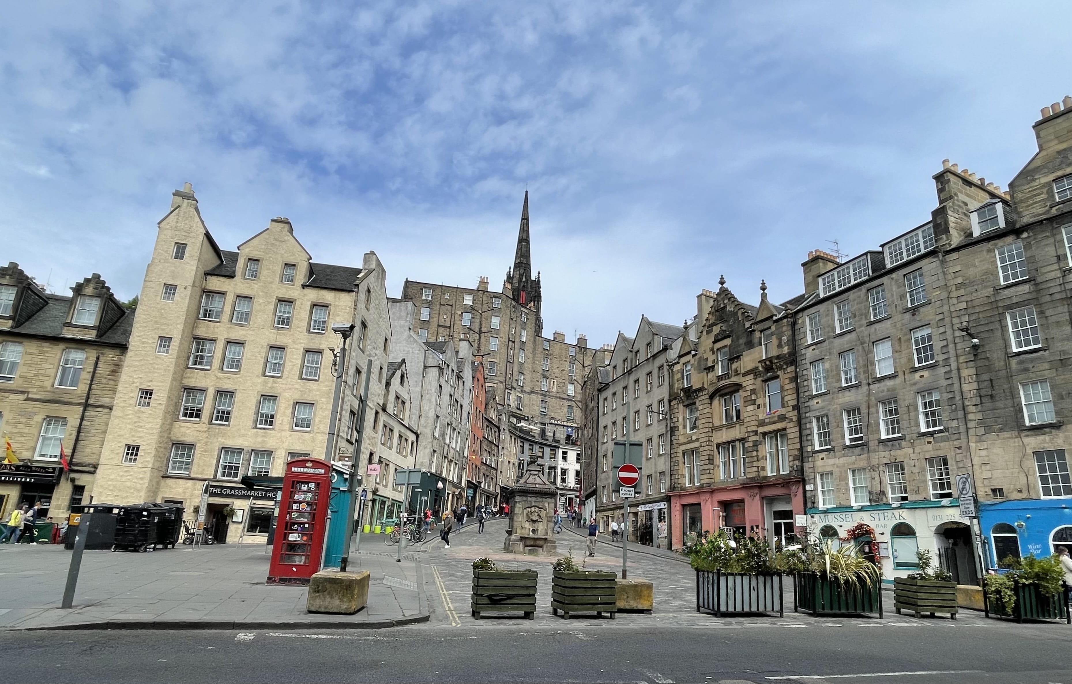 Wide view of Grassmarket Square in Edinburgh, lined with historic buildings, pubs, and cafés.
