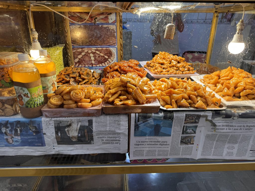 Assortment of Moroccan street sweets in a glass case, including chebakia and honey-drenched pastries, seen during 2 Days in Fes.