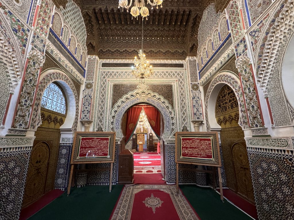 Interior of the Zaouia of Moulay Idriss II in Fes, Morocco, with ornate tilework, carved arches, and chandeliers, visited during 2 Days in Fes.