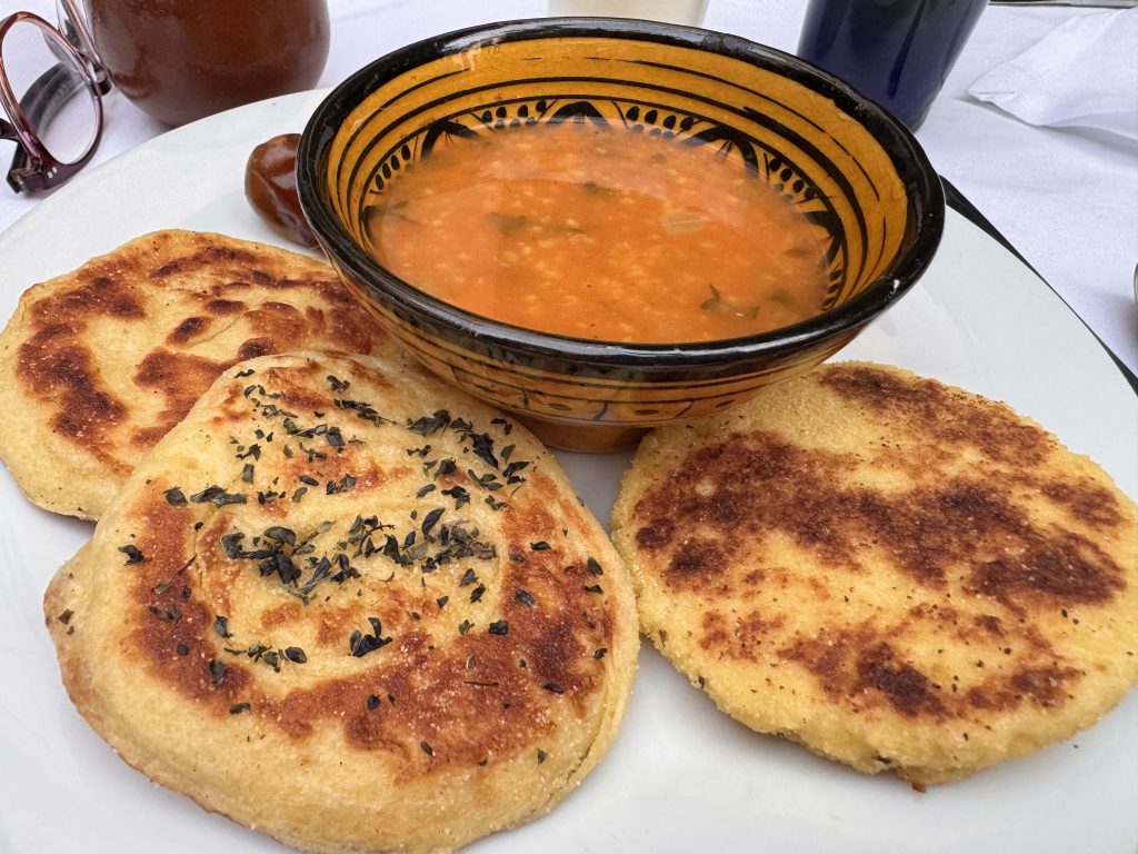 Moroccan breakfast with semolina bread, a sesame roll, and a bowl of warm soup, served at our riad during 2 Days in Fes.