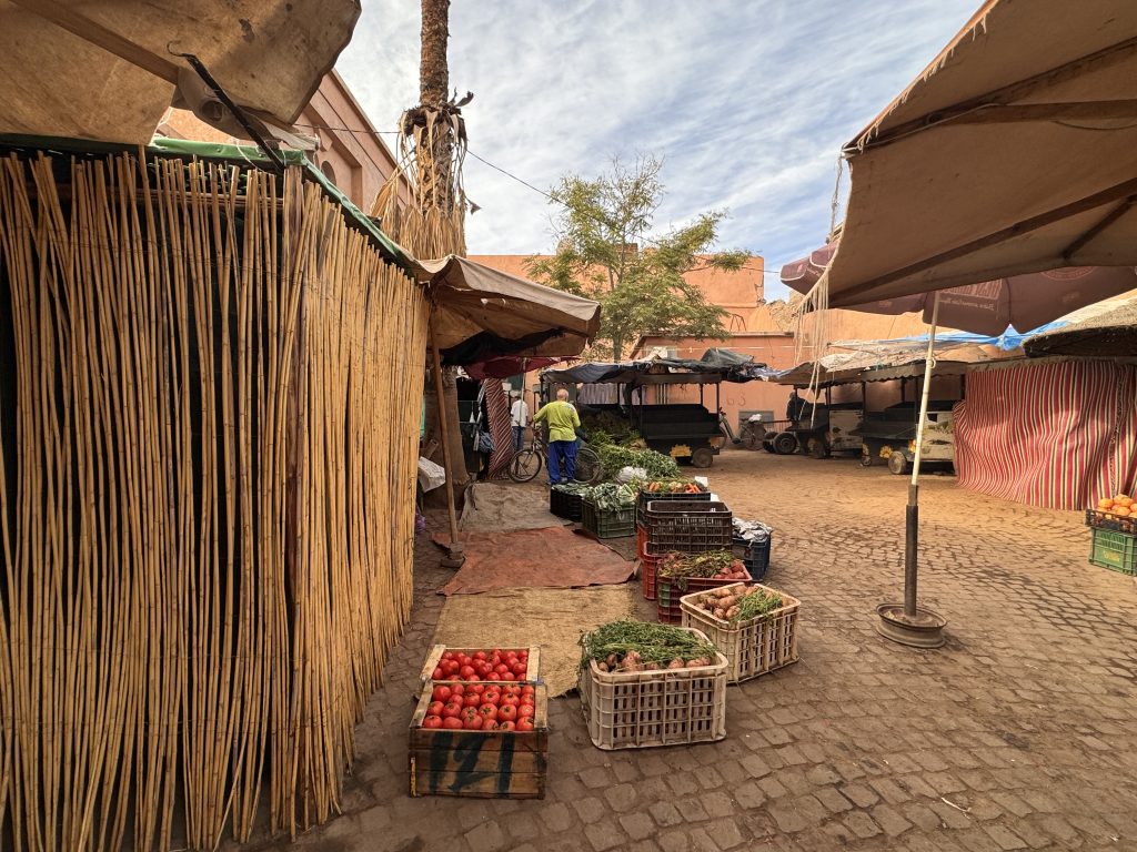 Crates of tomatoes, onions, and herbs displayed in an open-air market stall in Marrakech.
