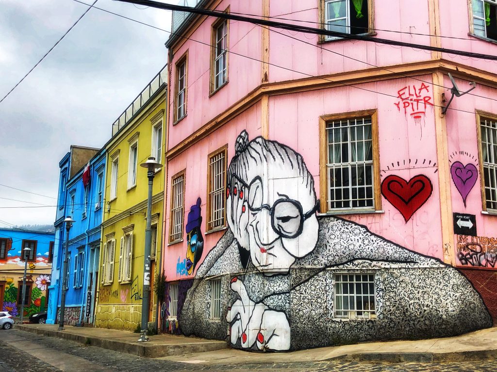 Colorful mural of an elderly woman with glasses on a pink building in Valparaíso, part of a coastal tour — 4 Days in Santiago, Chile.
