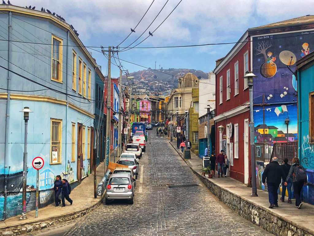 Cobblestone street in Valparaíso lined with colorful murals and houses, part of a coastal day trip — 4 Days in Santiago, Chile.