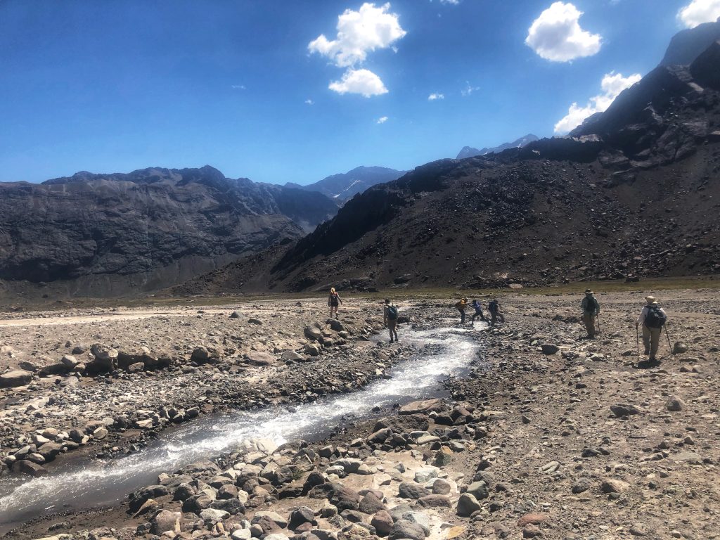 Group of hikers crossing a small stream in the Andes mountains near Santiago – outdoor adventure 4 days in Santiago.