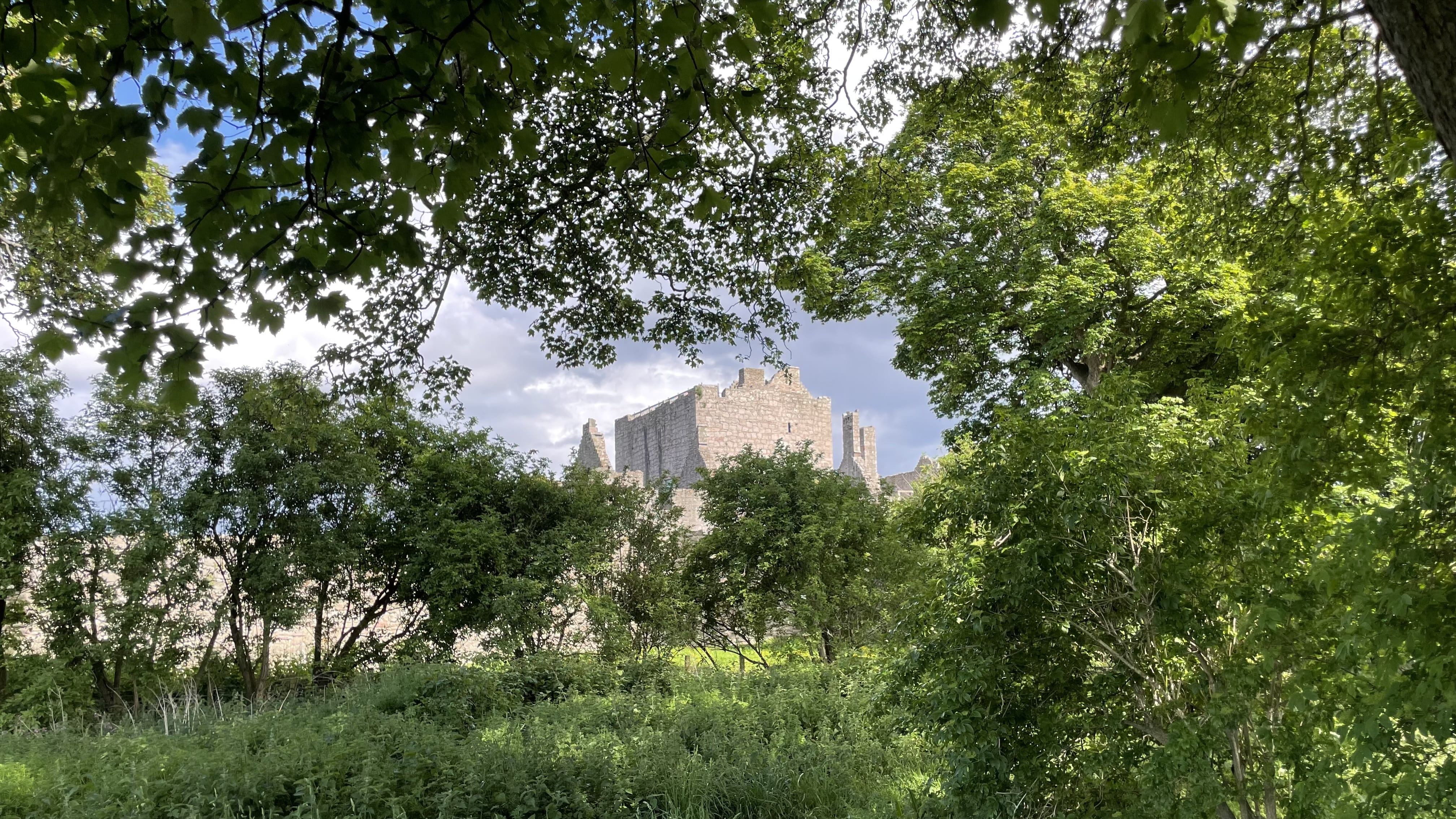View of Craigmillar Castle ruins partially hidden behind trees and greenery, during 4 days in Edinburgh.