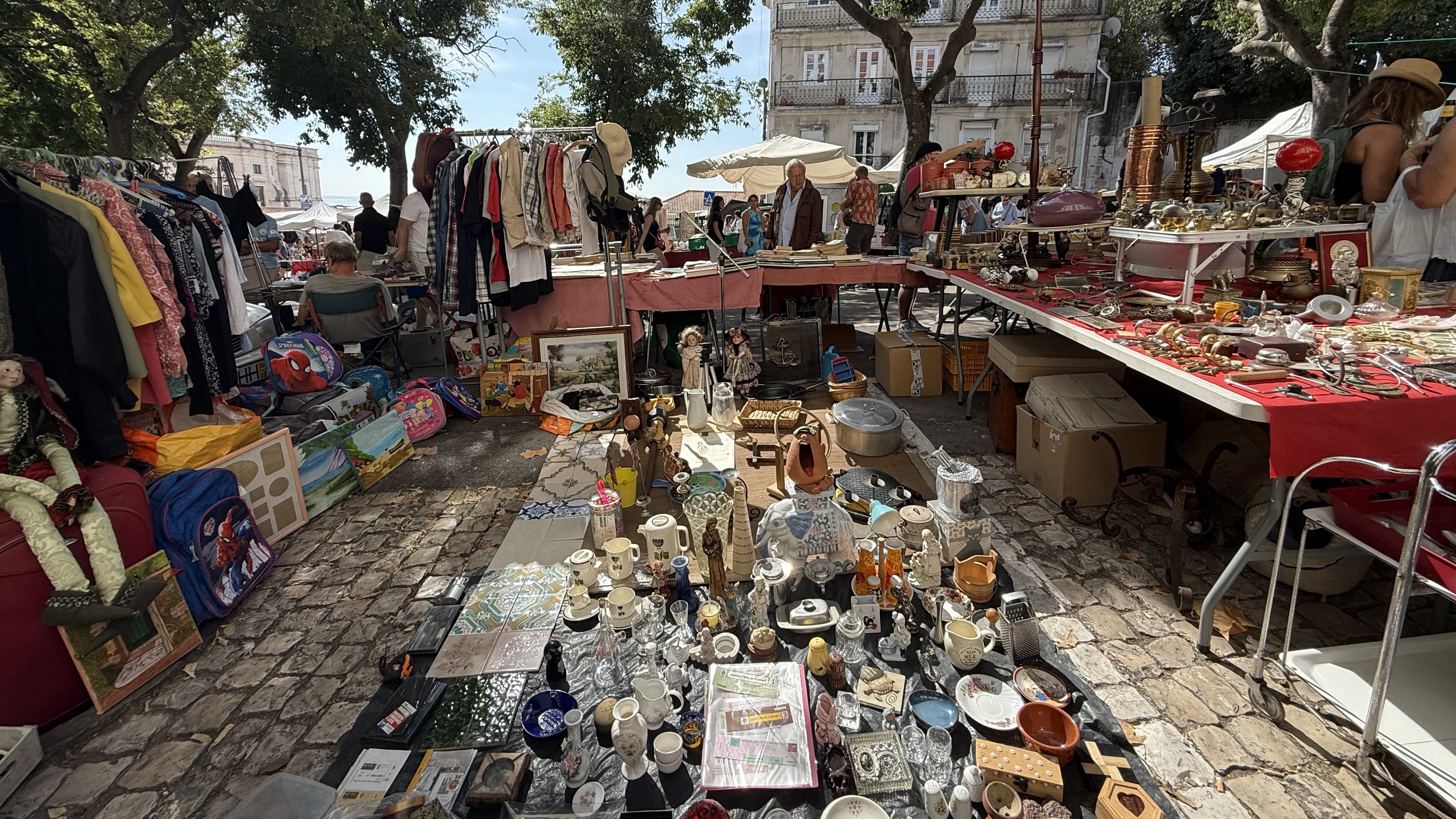 Table at Lisbon’s Thieves’ Market covered with glassware, figurines, and antiques.