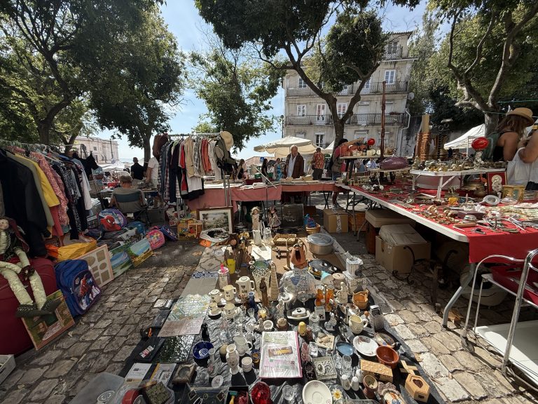 Table at Lisbon’s Thieves’ Market covered with glassware, figurines, and antiques.