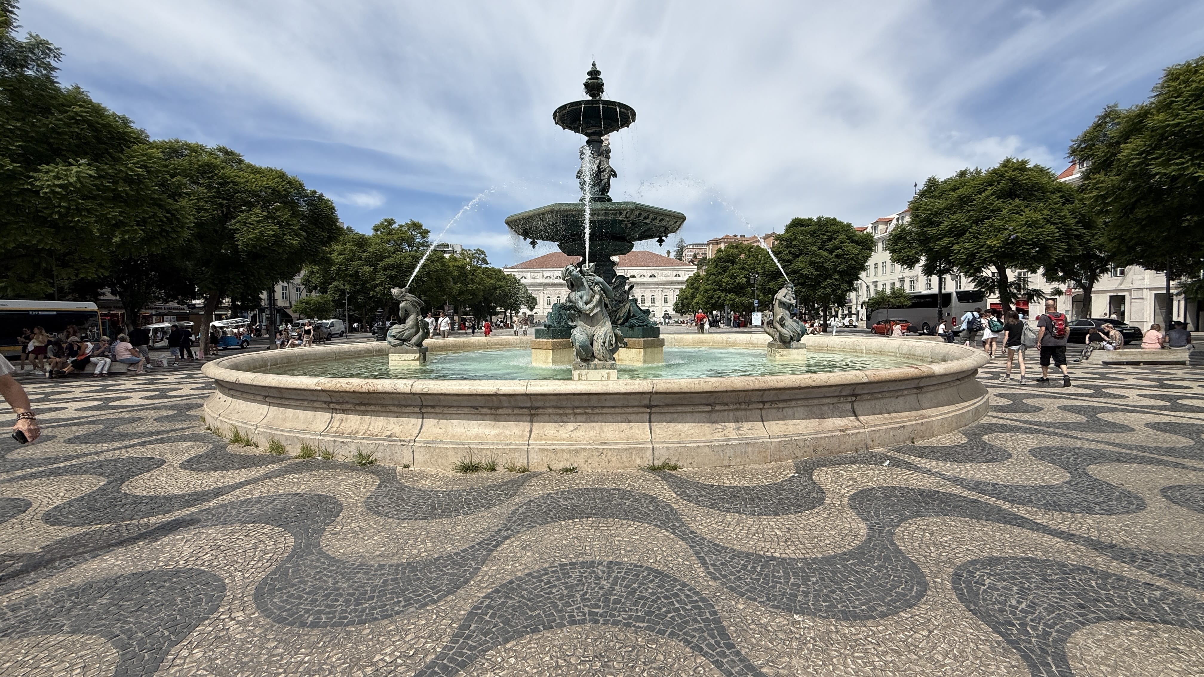 Ornamental fountain with wavy black-and-white calçada pavement in Rossio Square, Lisbon.