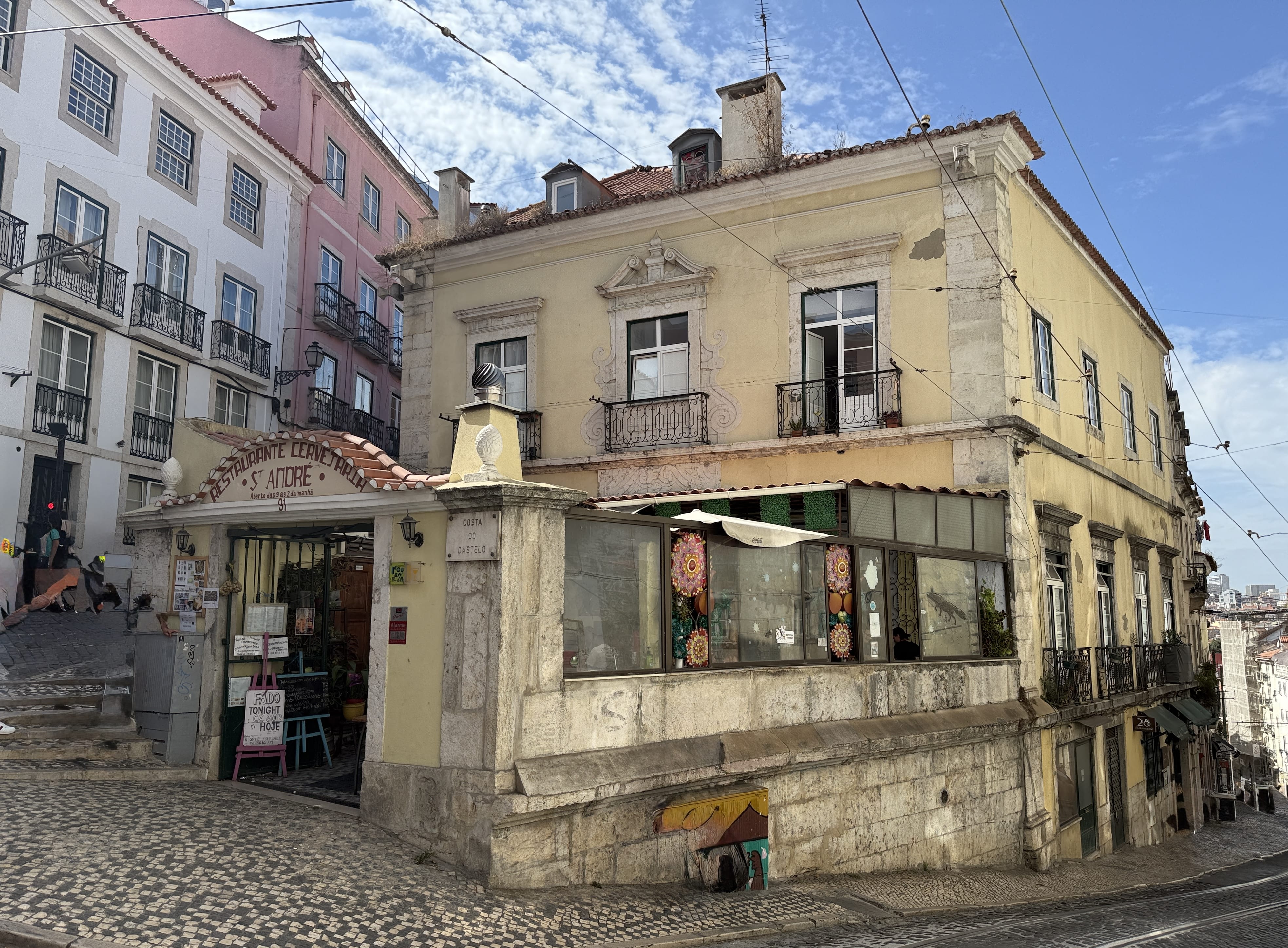 Historic yellow building in Lisbon’s Alfama district, home to Restaurante Leandro, a traditional Fado house with tiled pavement and narrow cobbled streets around it.