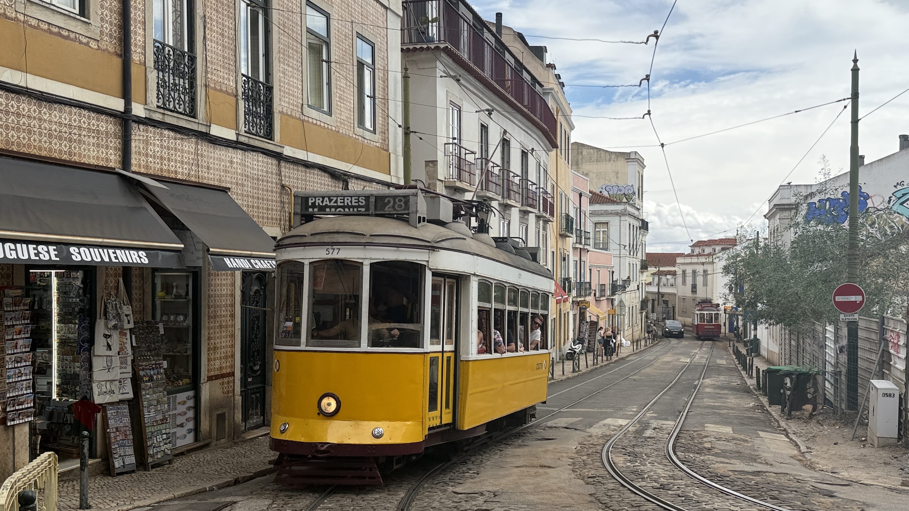 Historic yellow tram passing through the streets of Baixa, Lisbon, Portugal, with tiled sidewalks and old buildings in the background – 5 days in Lisbon travel blog.