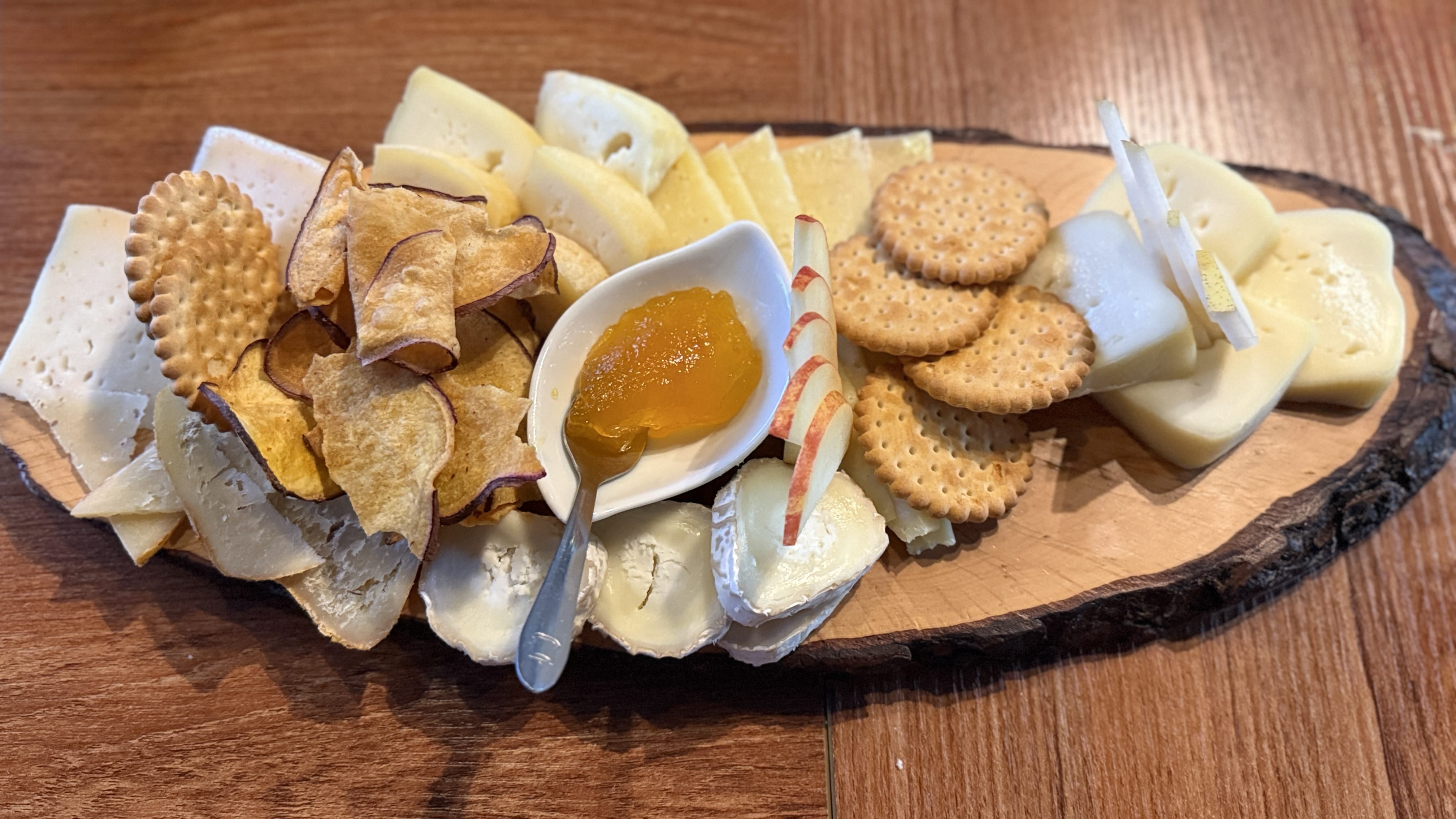 Wooden platter of assorted Portuguese cheeses with crackers, apple slices, sweet potato chips, and a dish of orange jam — 5 Days in Lisbon