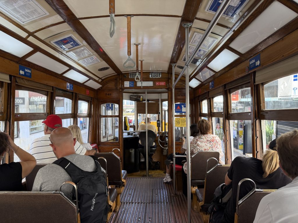 nterior of Lisbon’s historic Tram 28, with wooden seats, passengers, and views out to the city streets.
