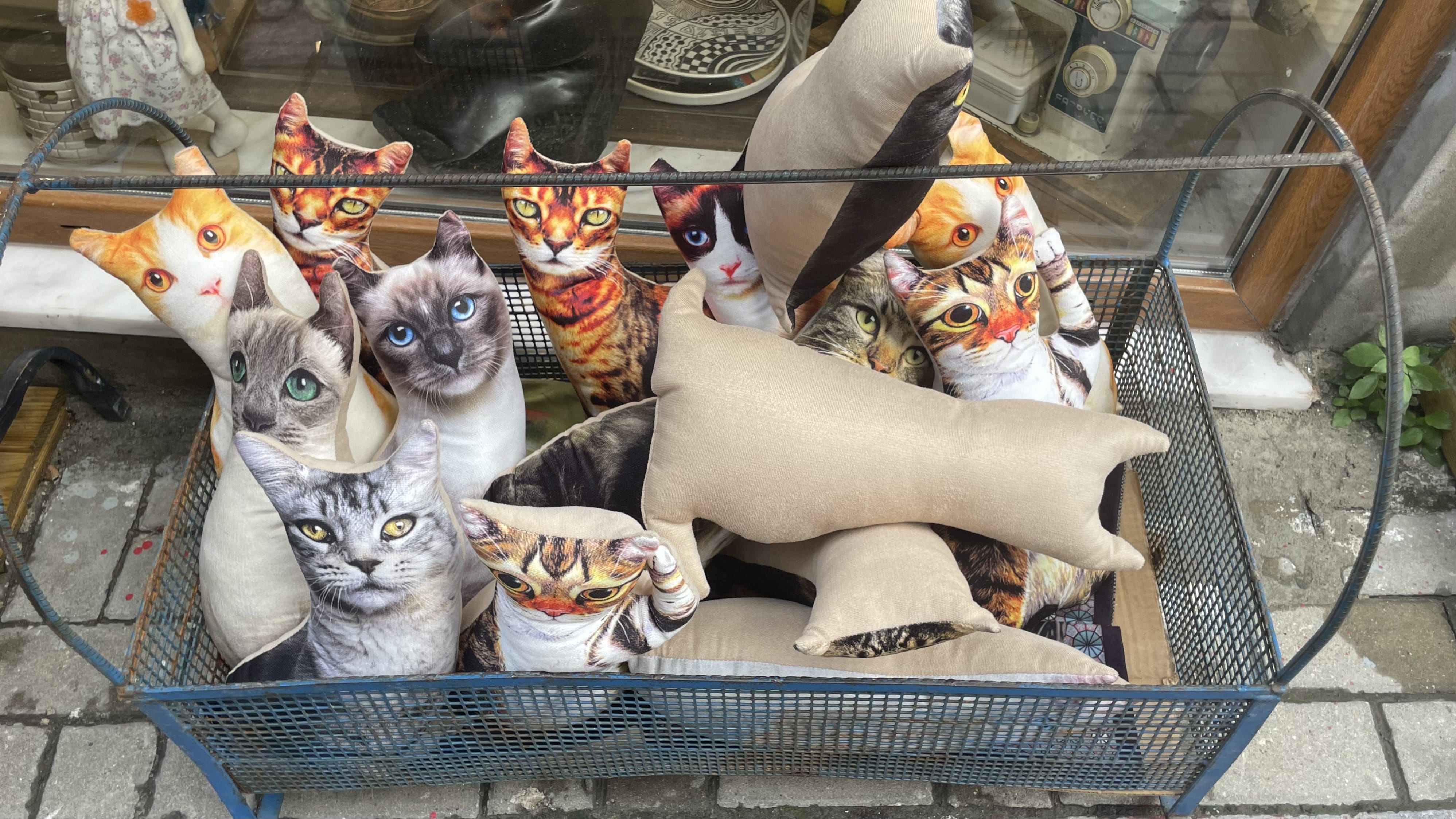 Basket filled with fabric pillows shaped like cats with printed feline faces in Istanbul.