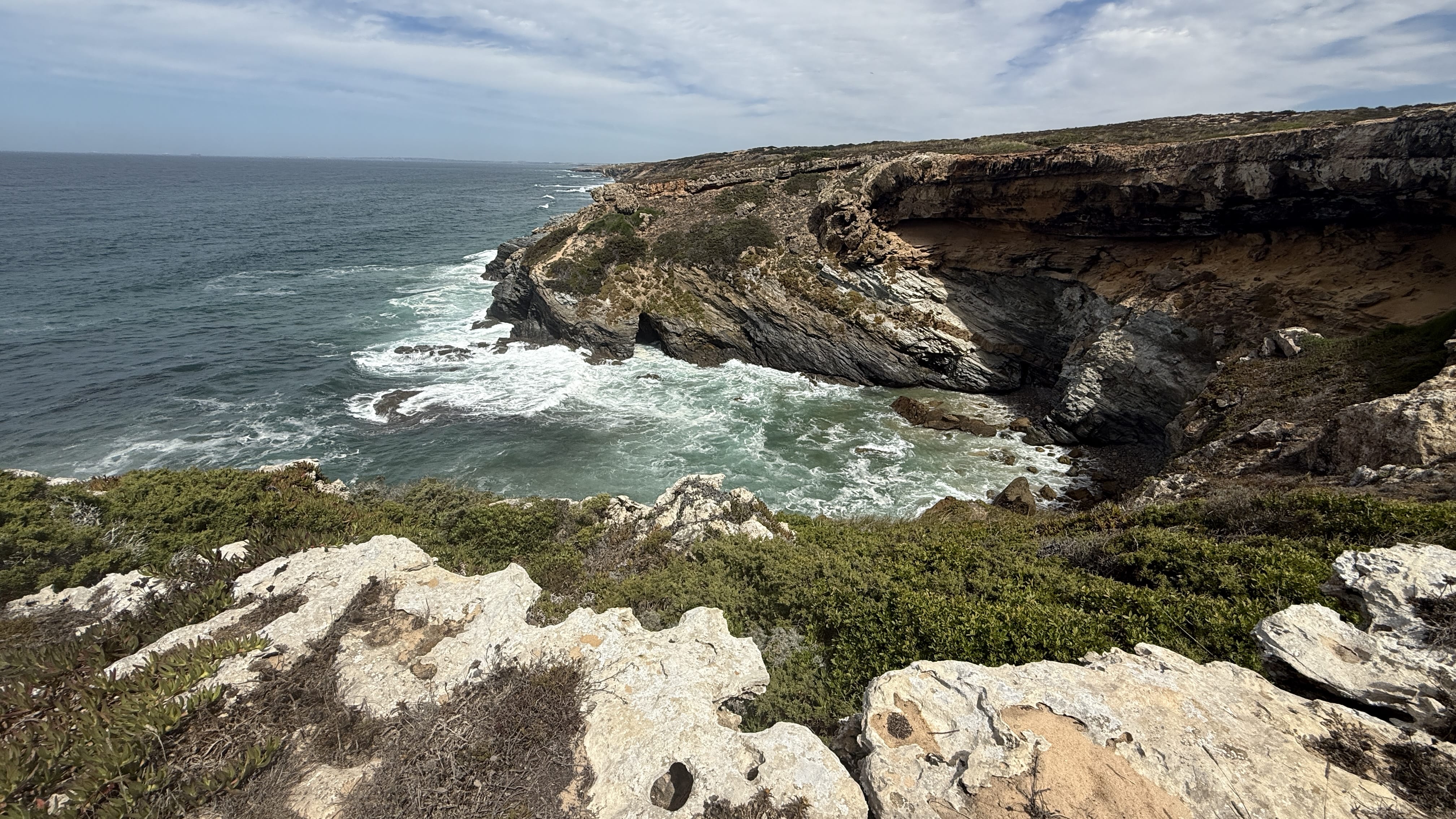 Rugged rocky cliffs and ocean waves along Portugal’s Fisherman’s Trail near Vila Nova de Milfontes.