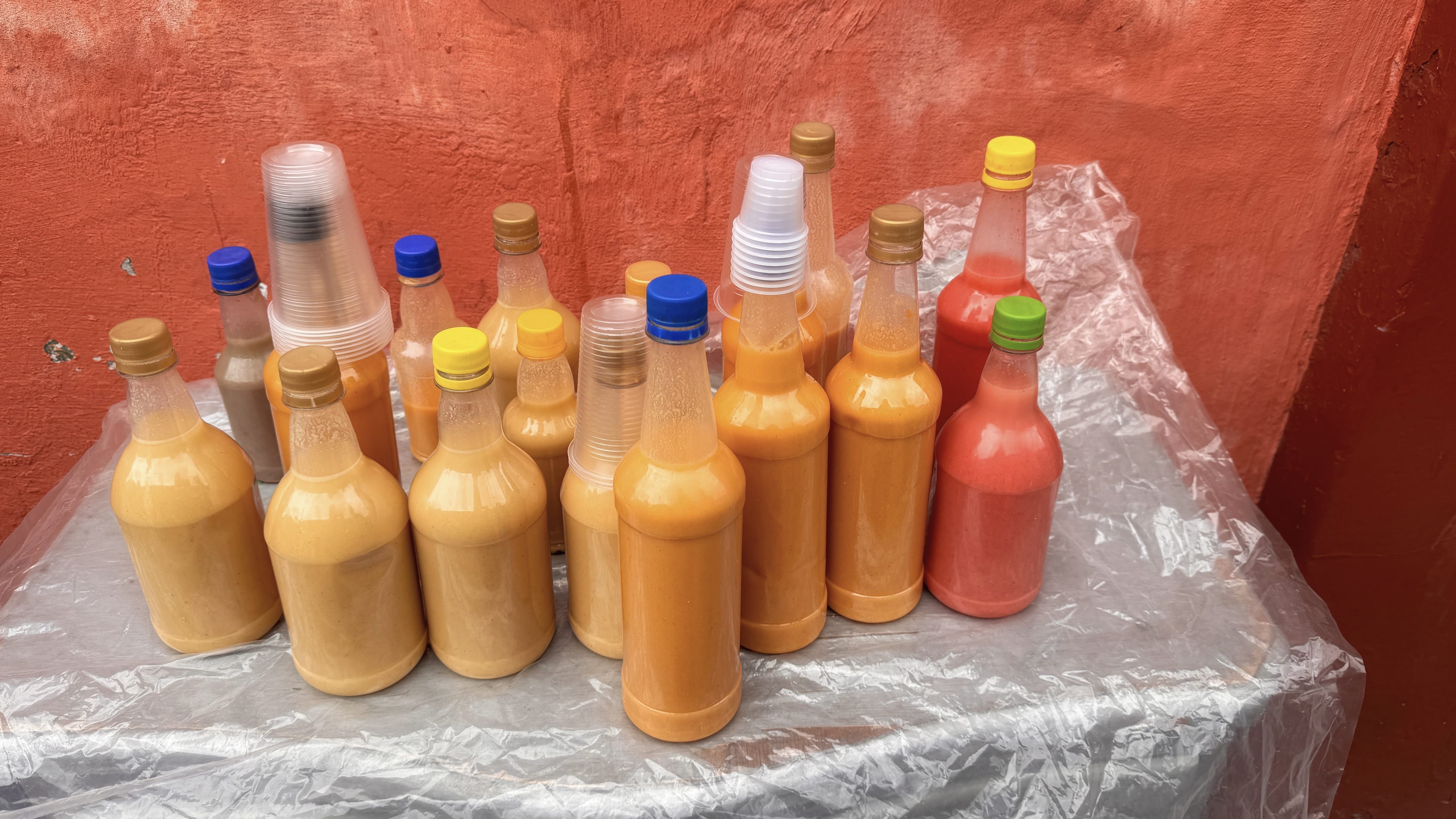 Plastic bottles filled with homemade chicha, a traditional corn-based drink, on display at a Bogotá street market.