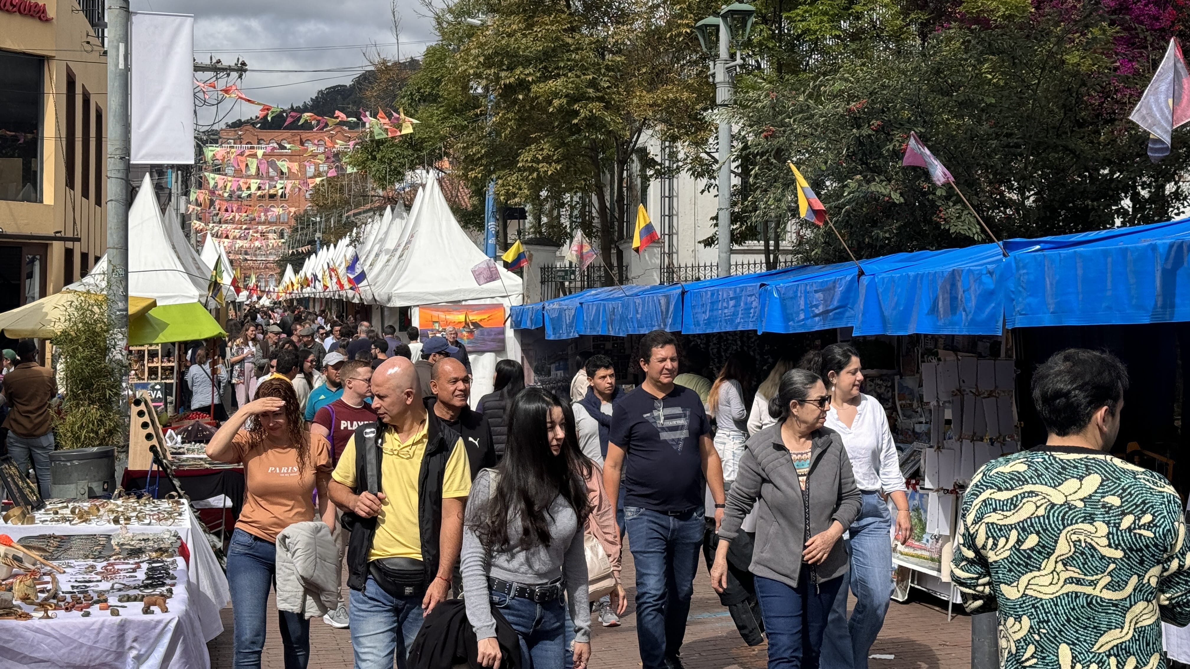 Crowds browsing stalls at a busy outdoor street market in Bogotá, Colombia