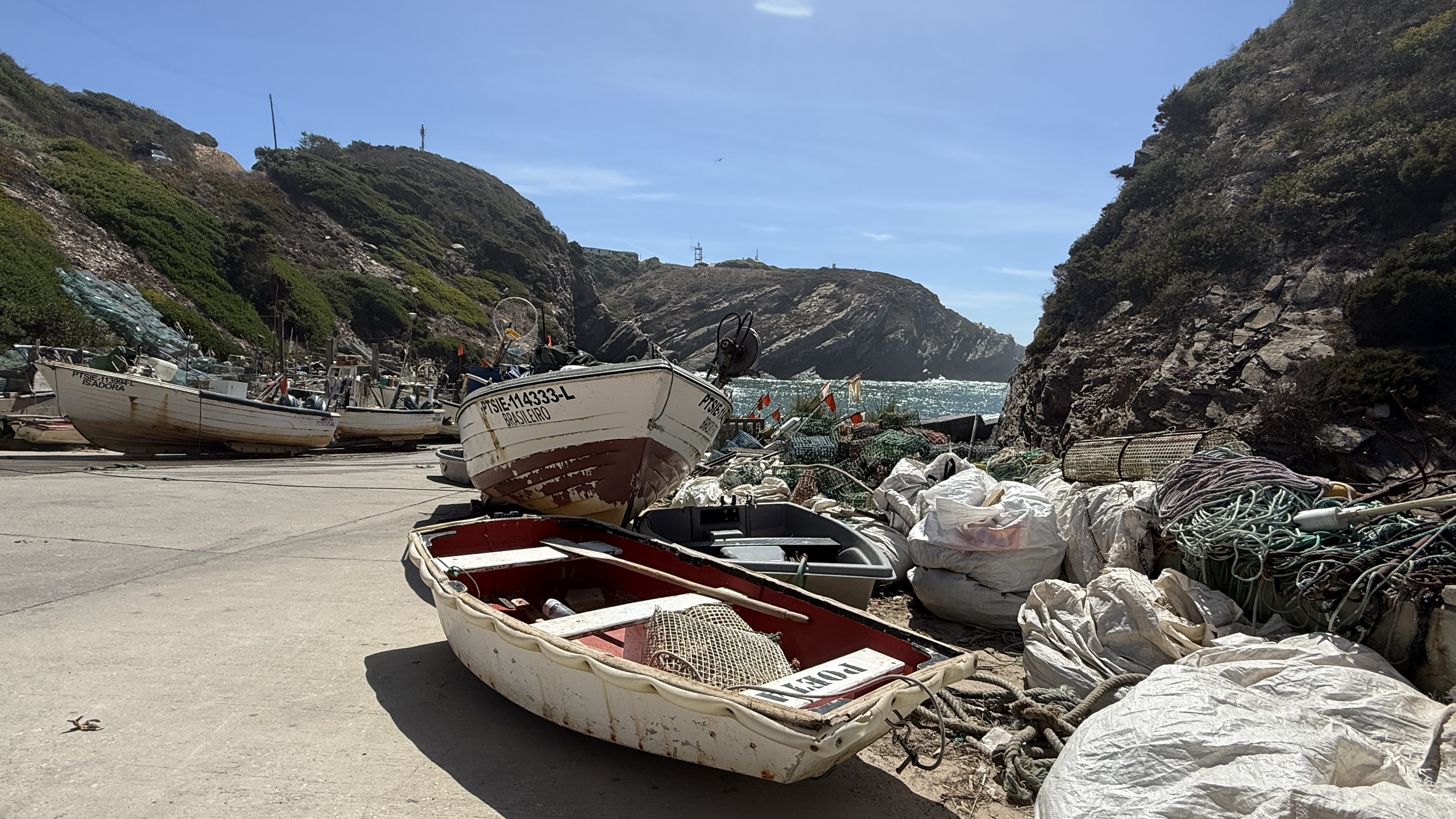 Traditional Portuguese fishing boats and piles of nets at the small port of Entrada da Barca, Alentejo coast.