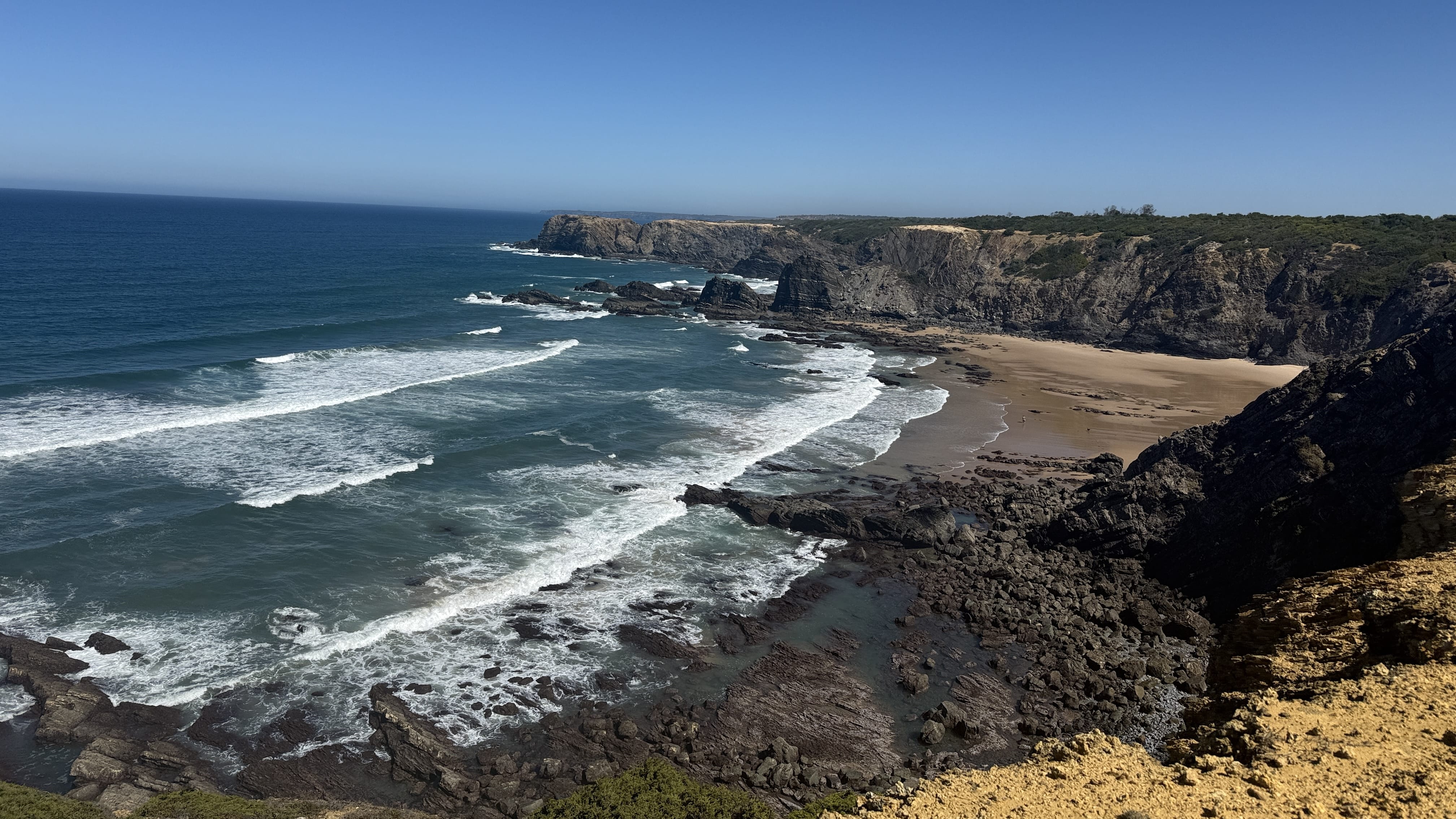 Wide view of Praia de Machados with golden sand and surrounding cliffs along the Fisherman’s Trail, Portugal.