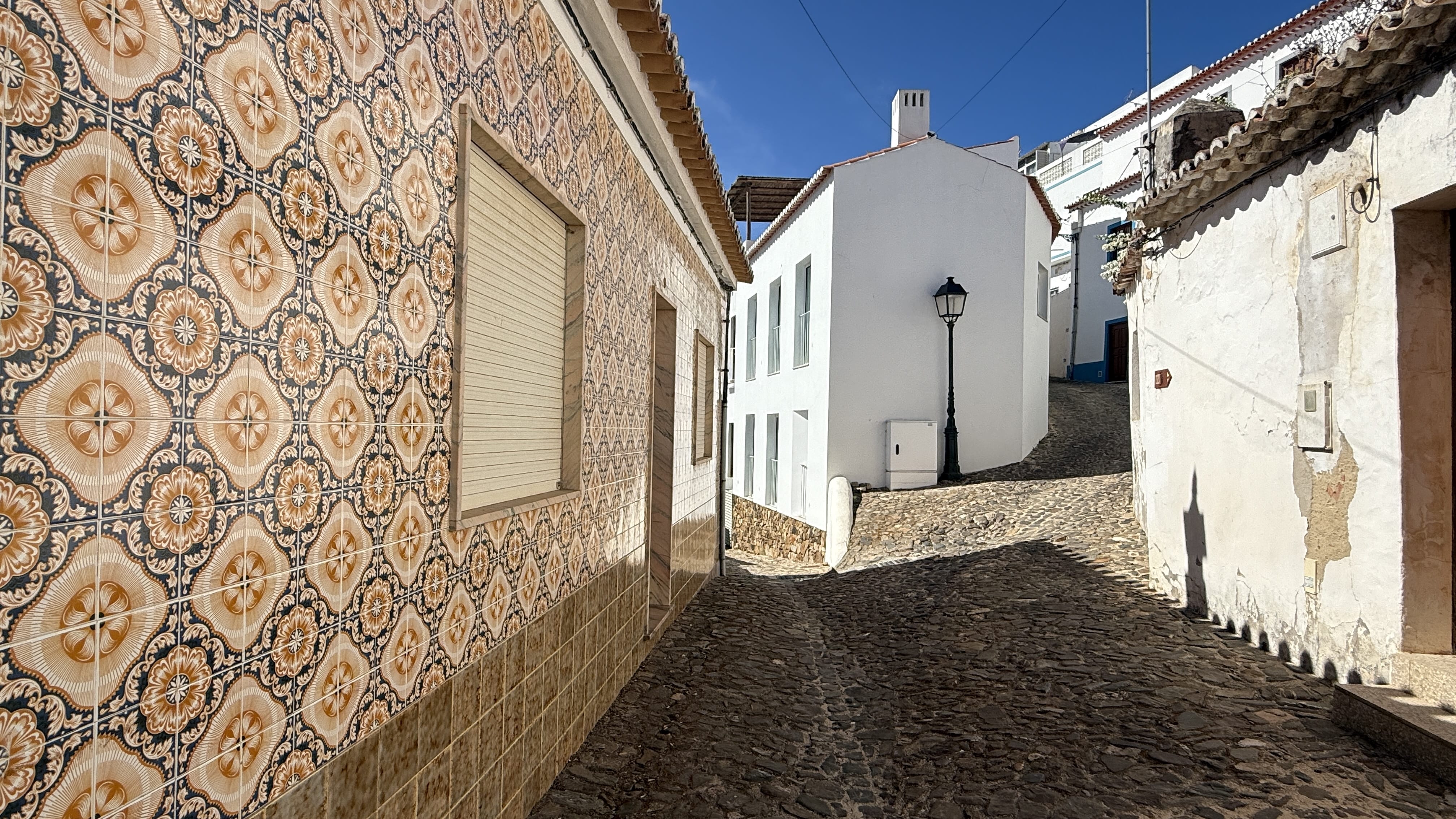 Decorative tiled house wall along a cobblestone street in Aljezur, Portugal.