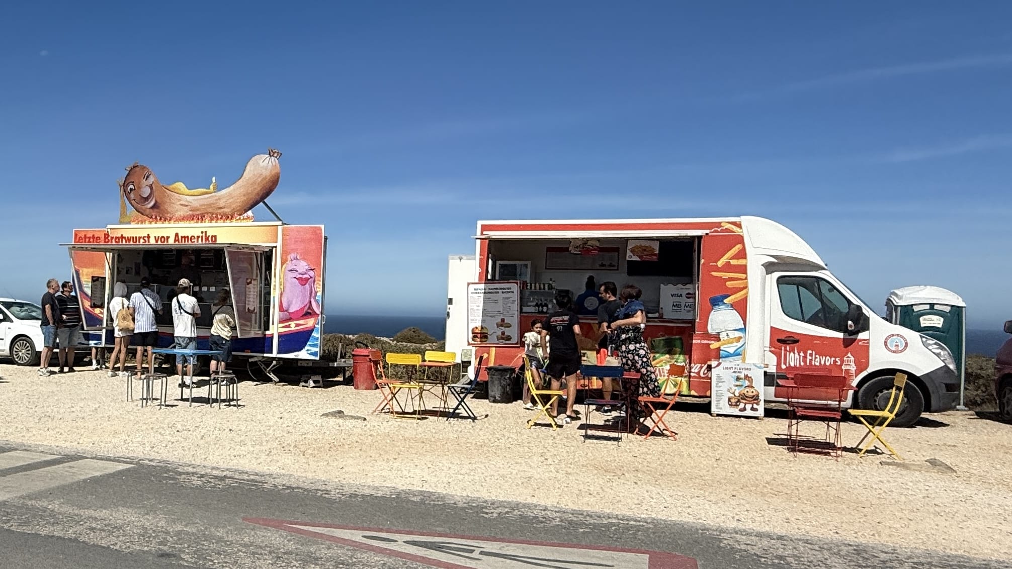 Food truck at Cabo de São Vicente in Portugal with a sign reading “Letzte Bratwurst vor Amerika” (“Last Sausage Before America”), a playful stop for visitors at Europe’s southwestern tip.