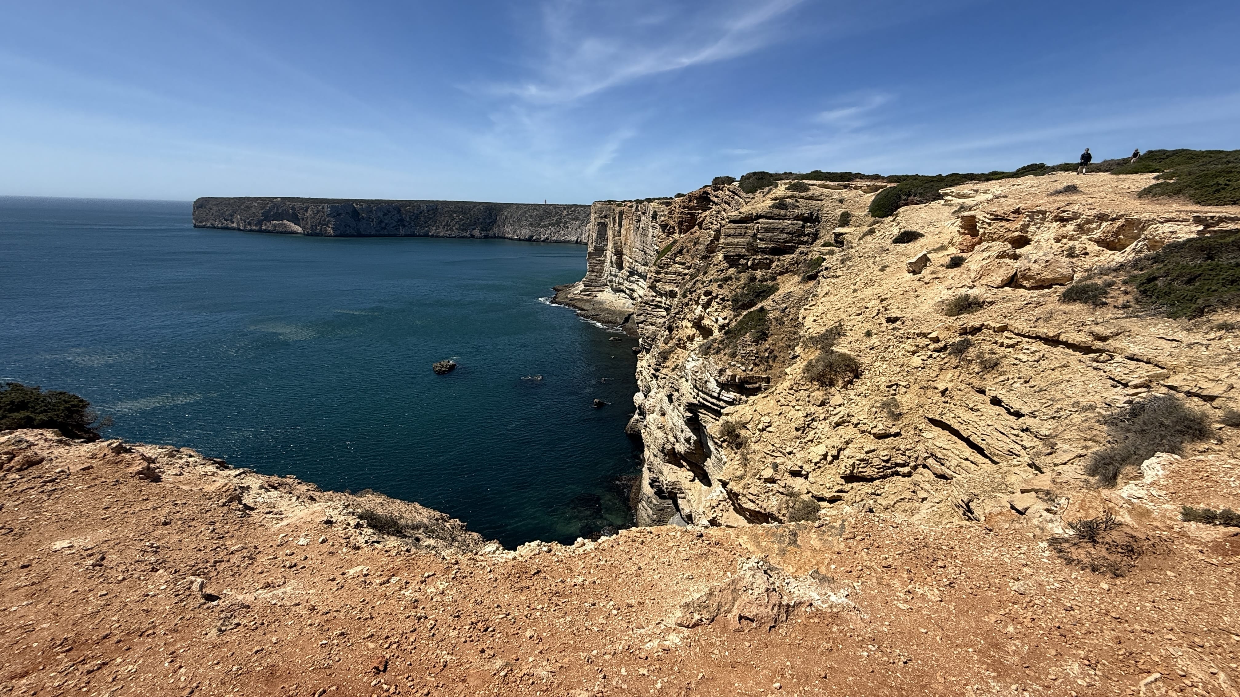 Sheer golden cliffs rising above the deep blue Atlantic, with waves breaking far below.