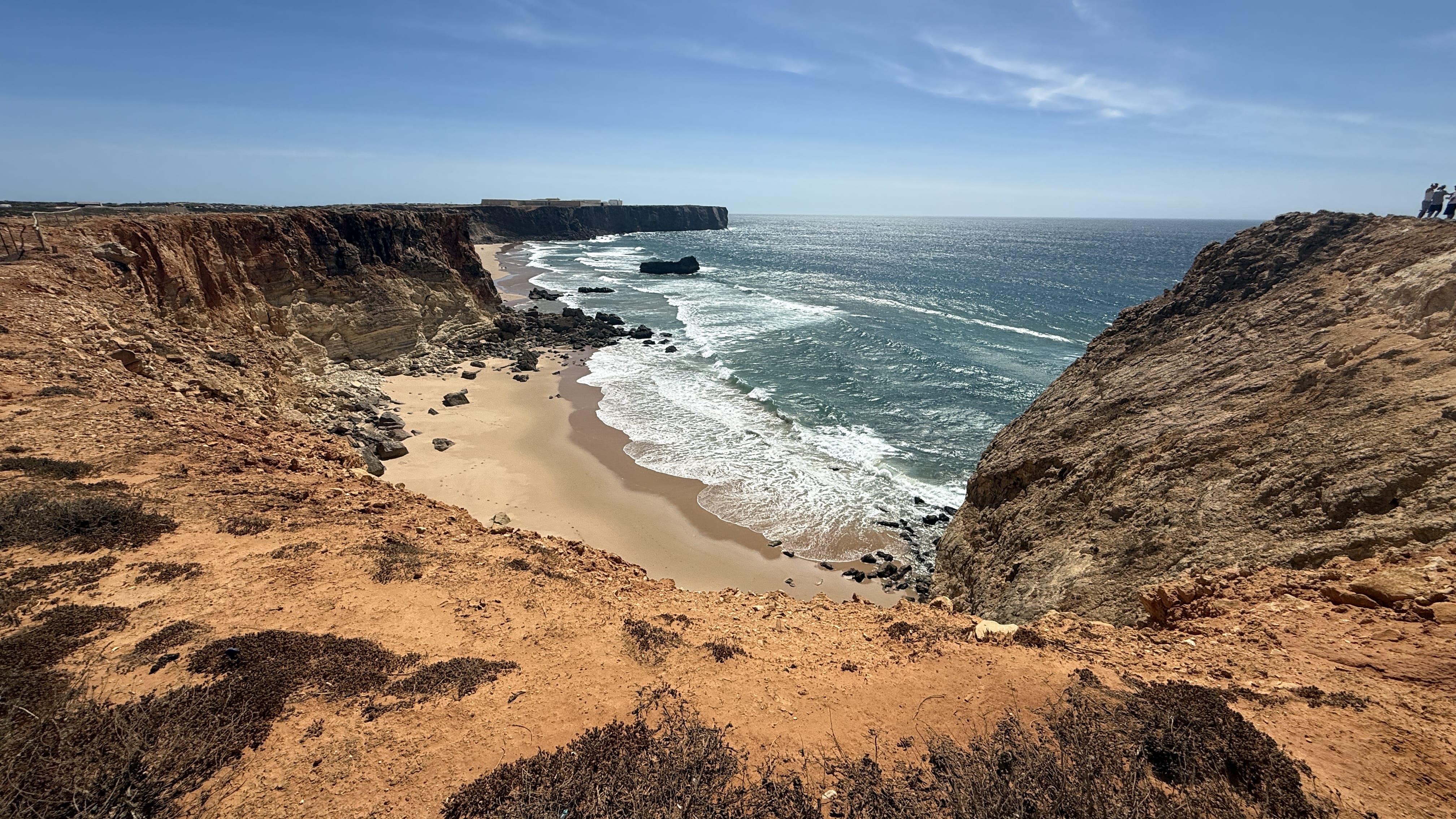 Sheer golden cliffs rising above the deep blue Atlantic, with waves breaking far below.