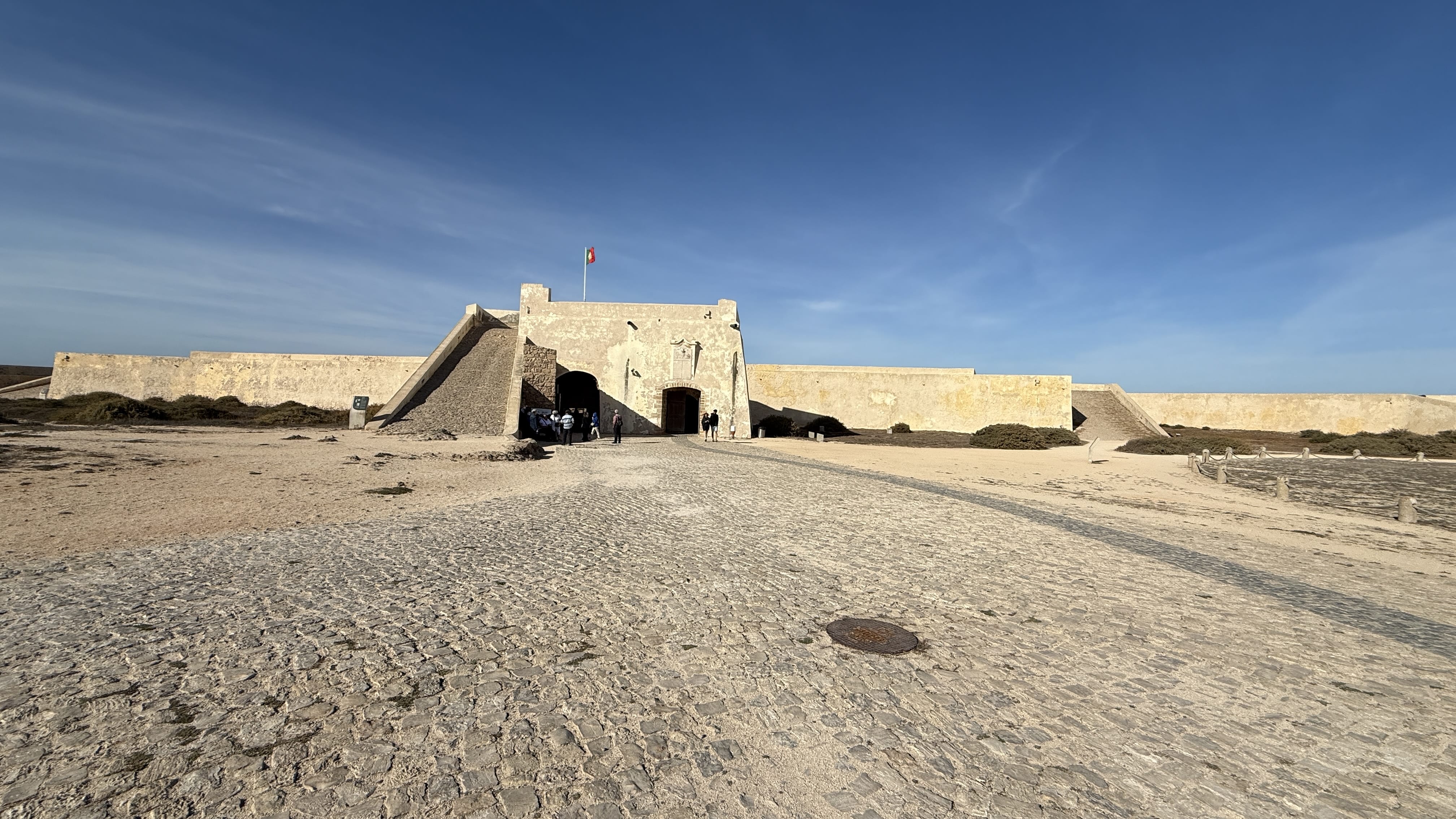 Wide view of the Sagres Fortress walls and entrance under a clear blue sky.