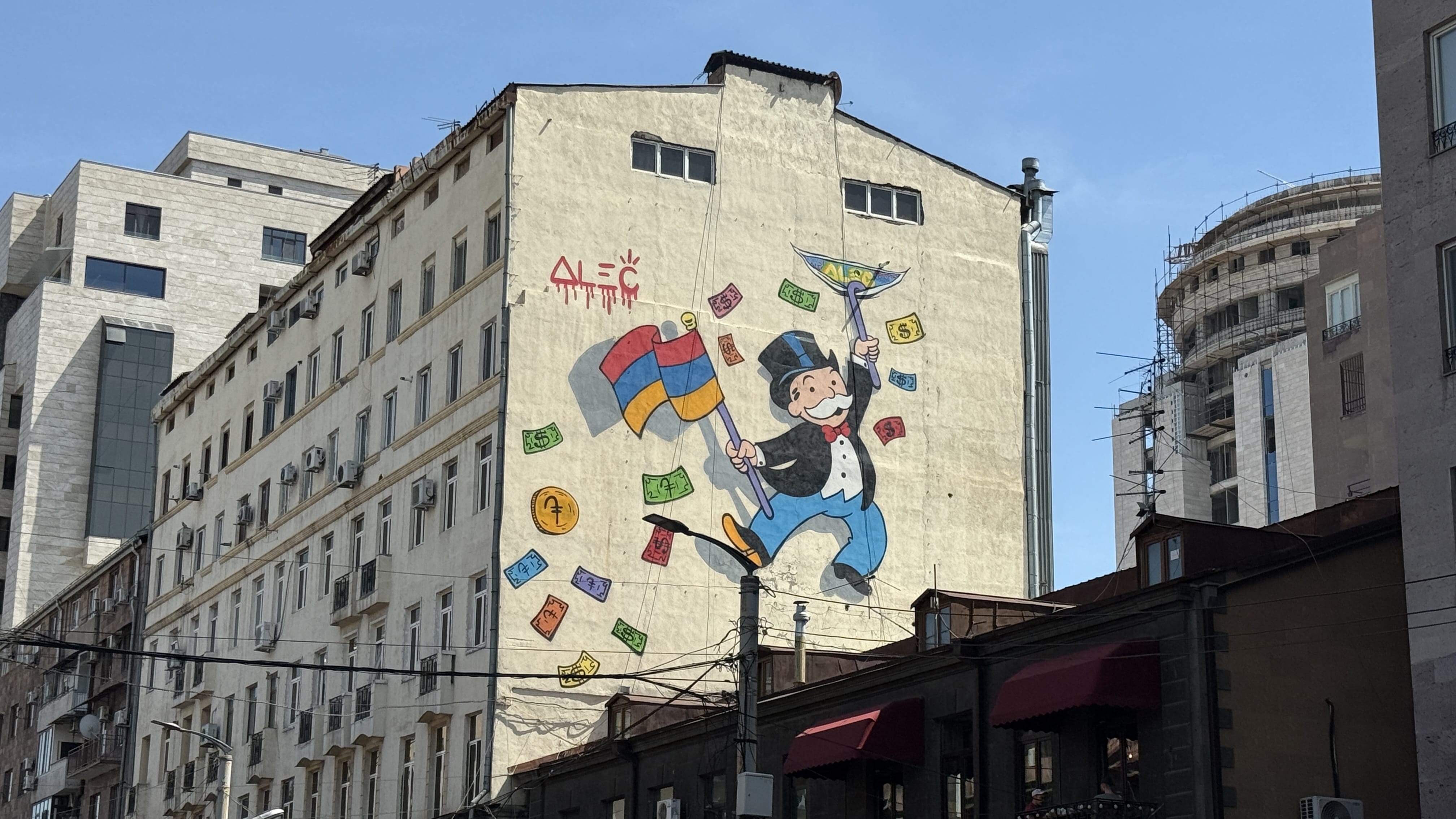 Street art mural of Monopoly Man holding the Armenian flag and juggling money, painted by Alec Monopoly in Yerevan, Armenia.