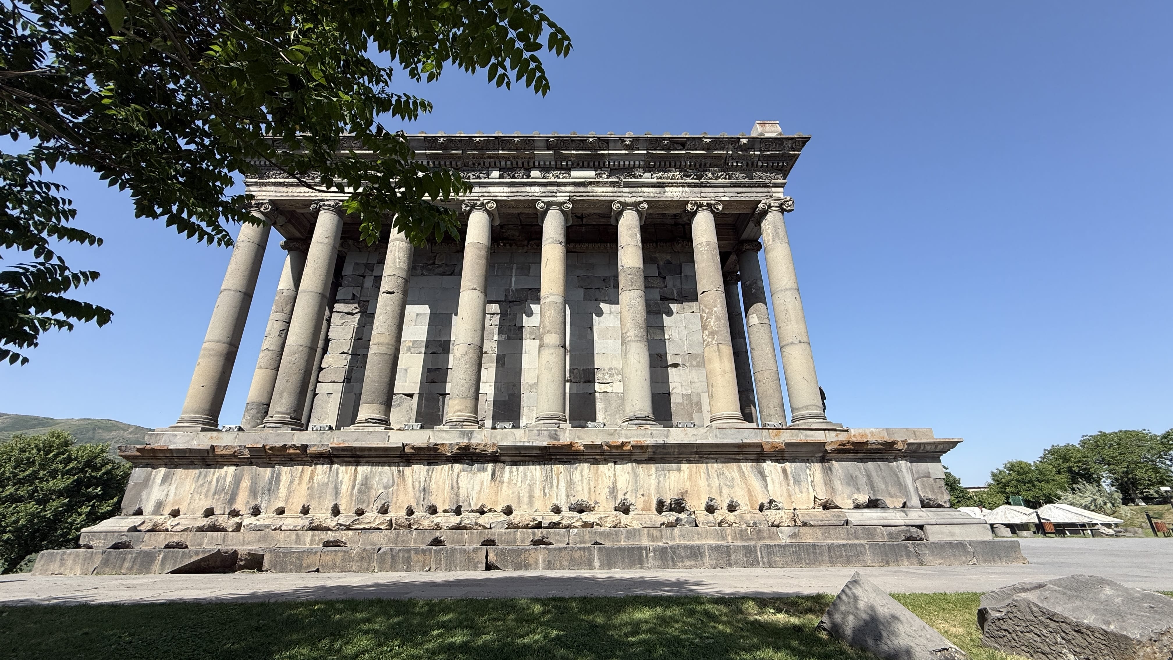 Seven Days in Armenia – side view of Garni Temple’s basalt columns and decorated façade framed by tree branches.