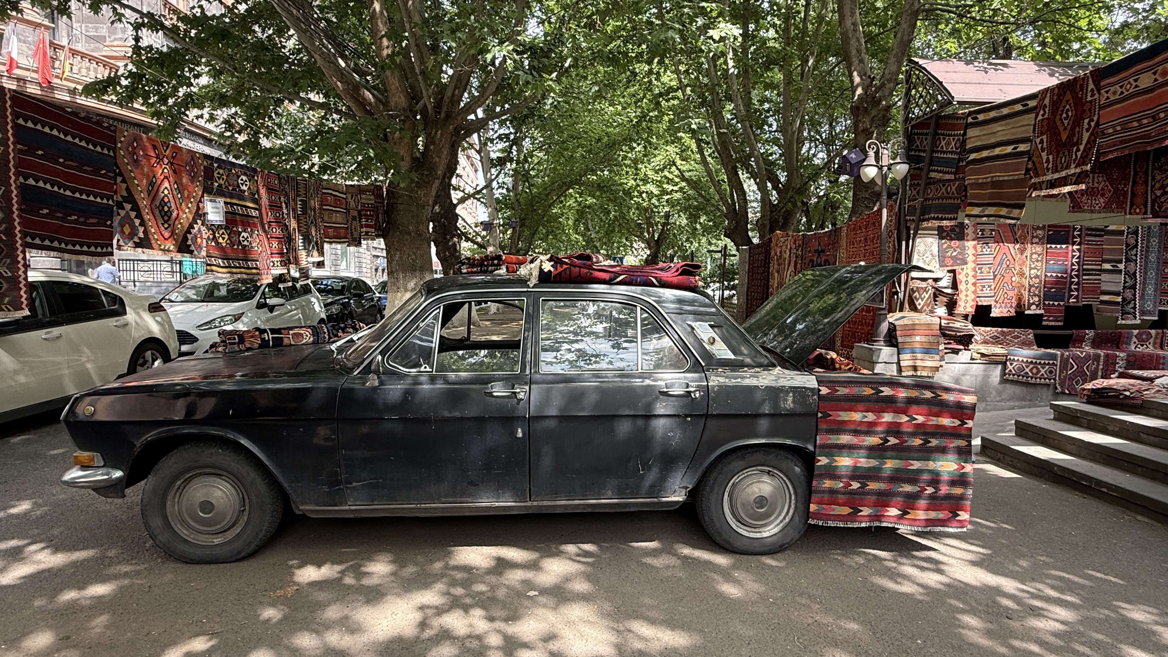Old Soviet-era car covered in Armenian carpets, parked outside a rug shop in Yerevan – 24 Hours in Yerevan.