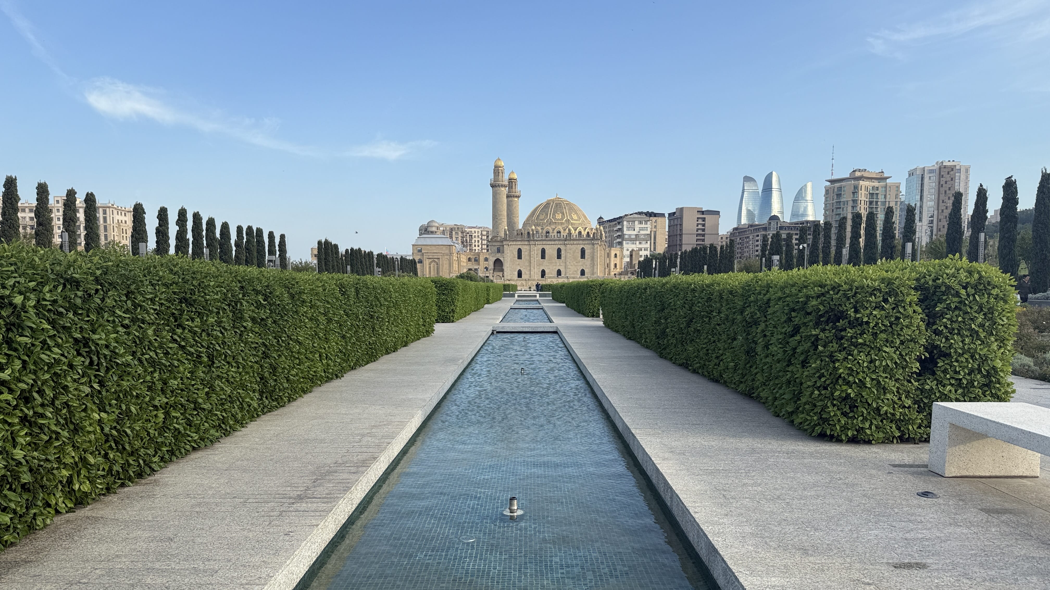 Teze Pir Mosque in Baku, Azerbaijan, with its golden dome and twin minarets rising above manicured gardens near the city center.