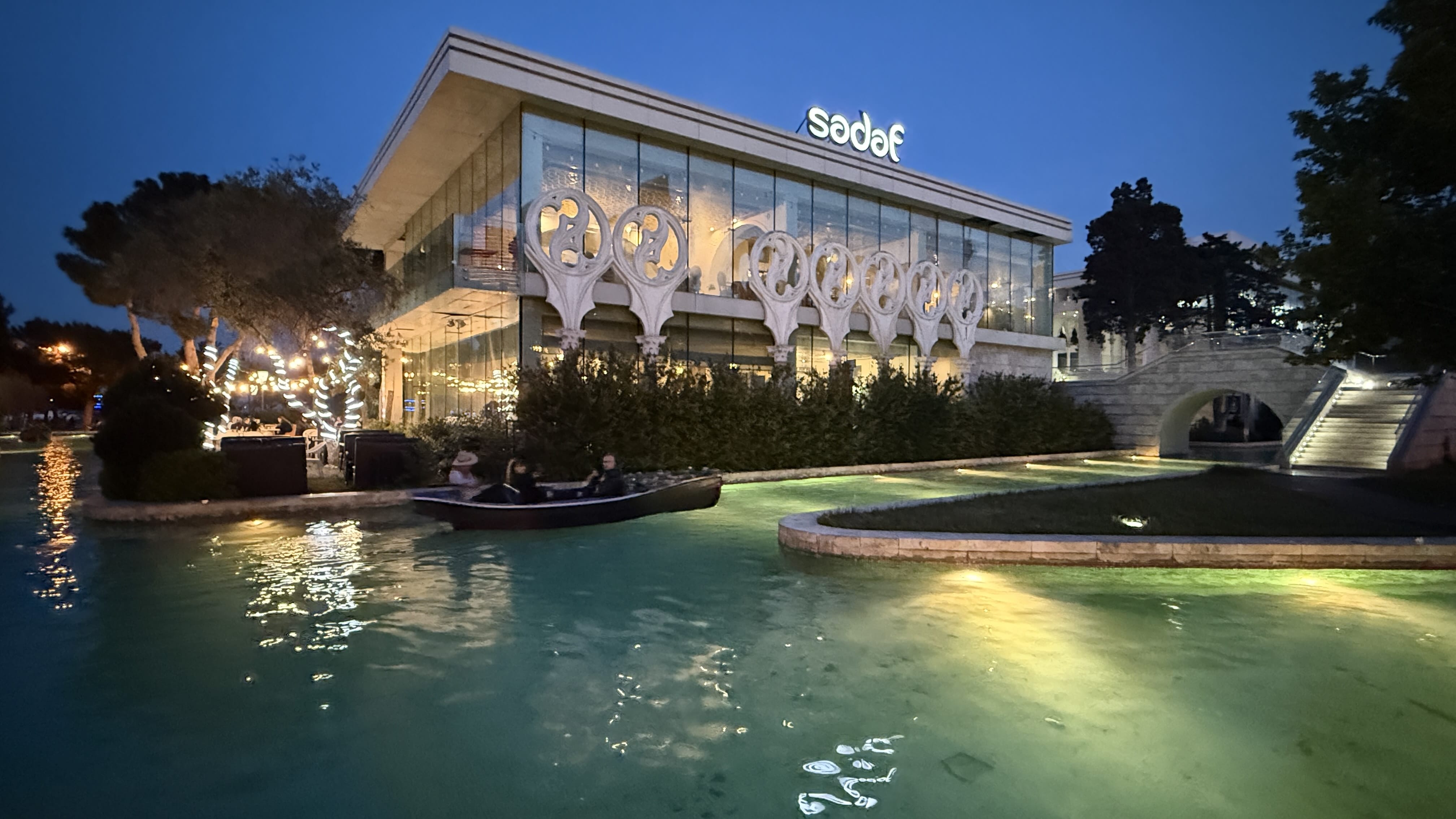 Evening view of Baku’s Little Venice, with a canal lit by soft lights and a small boat gliding past.