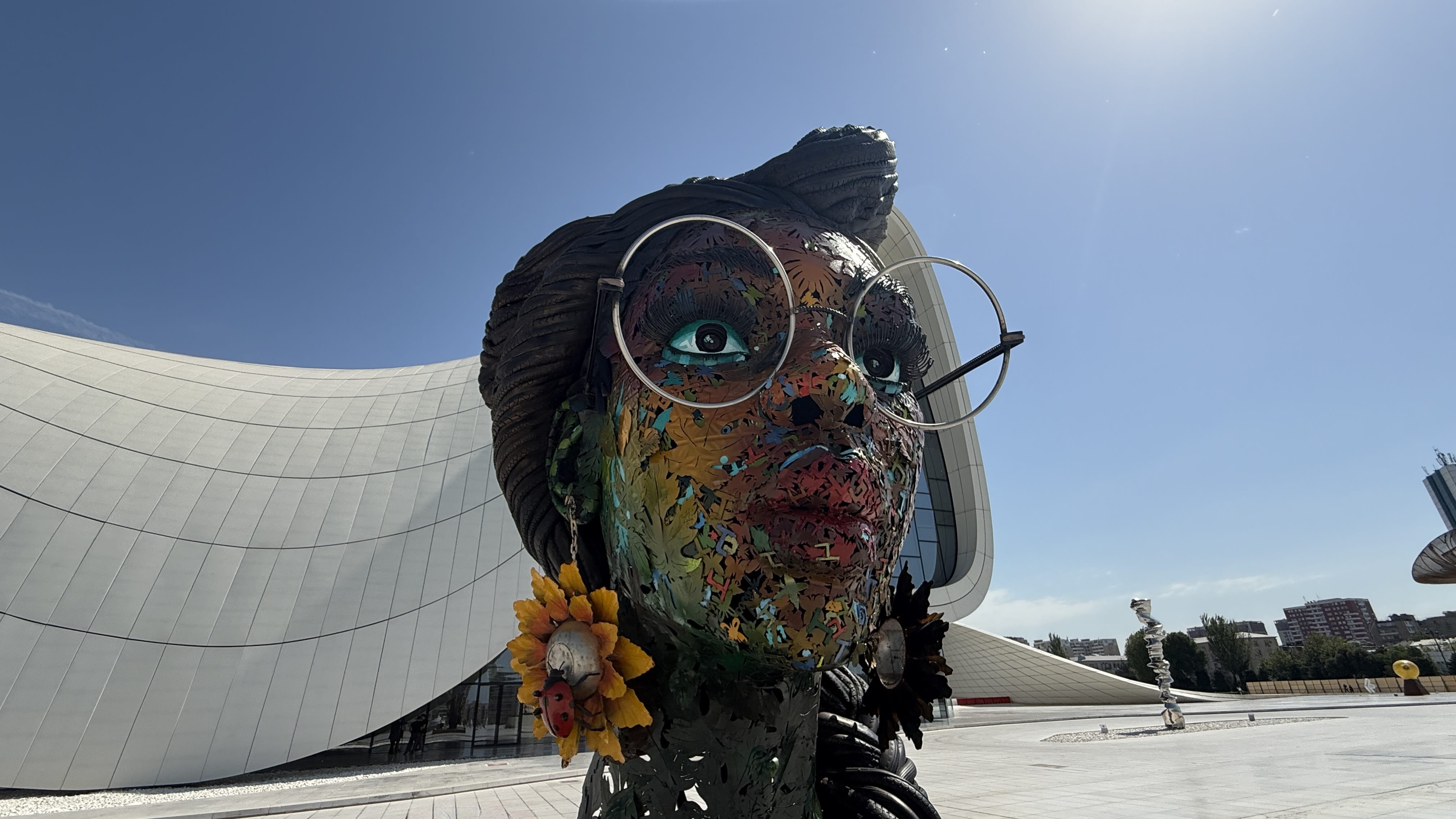 Colorful female sculpture with large glasses and sunflower earrings by Dotun Popoola, displayed outside Heydar Aliyev Center — 2 Days in Baku outdoor art.