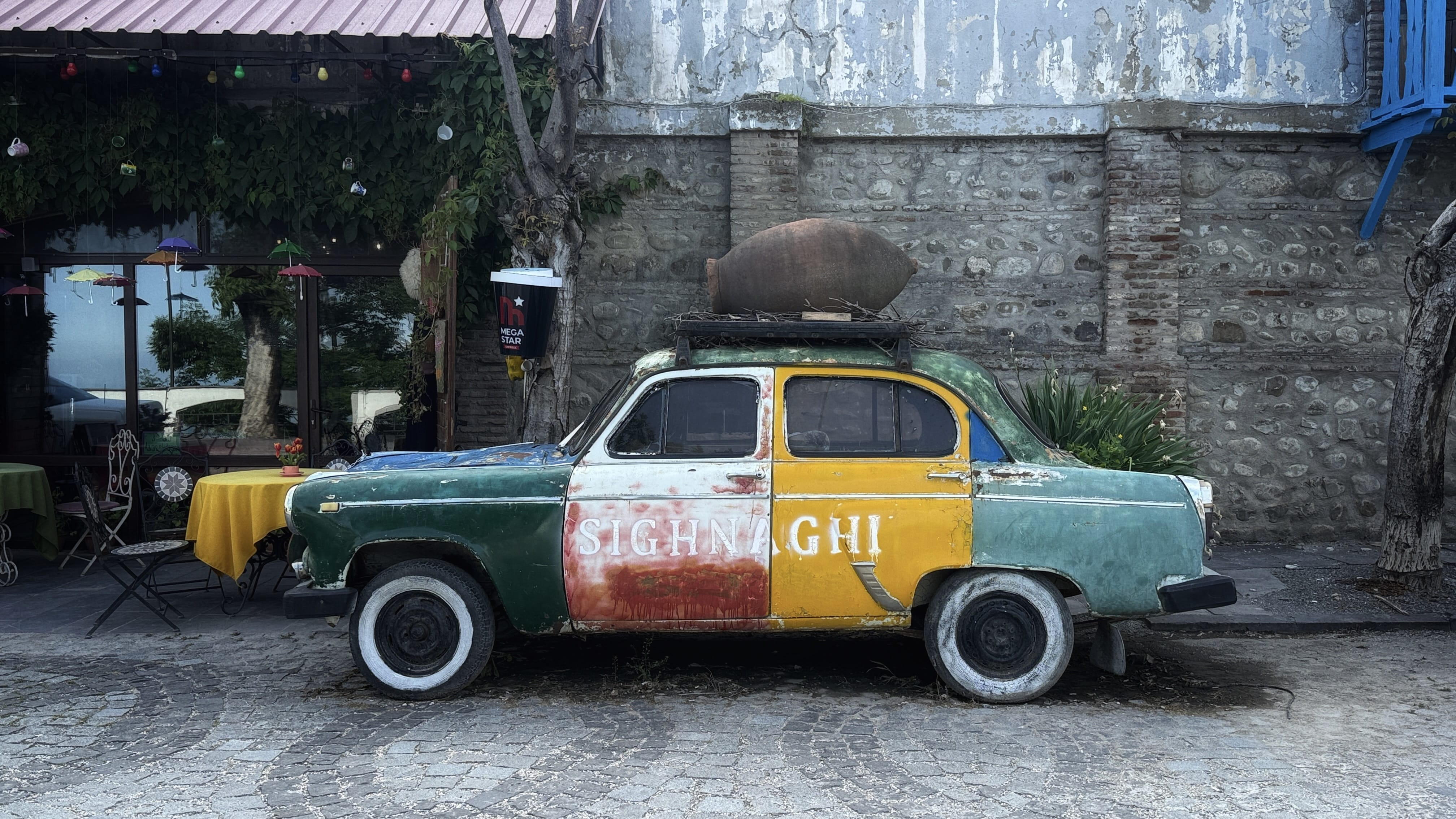 Vintage Soviet-era car painted green, yellow, and red parked in Sighnaghi, Georgia, along a cobblestone street during a 7 days in Georgia itinerary.