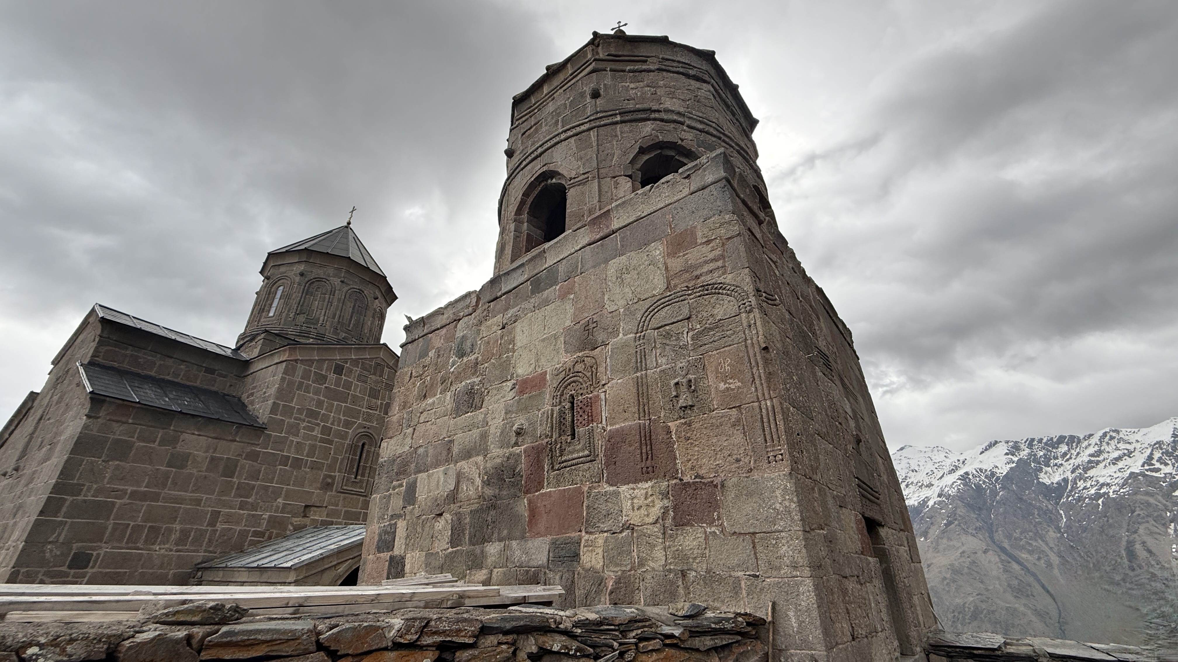 Stone exterior of Gergeti Trinity Church near Mount Kazbek in Georgia, with carved details and mountain backdrop