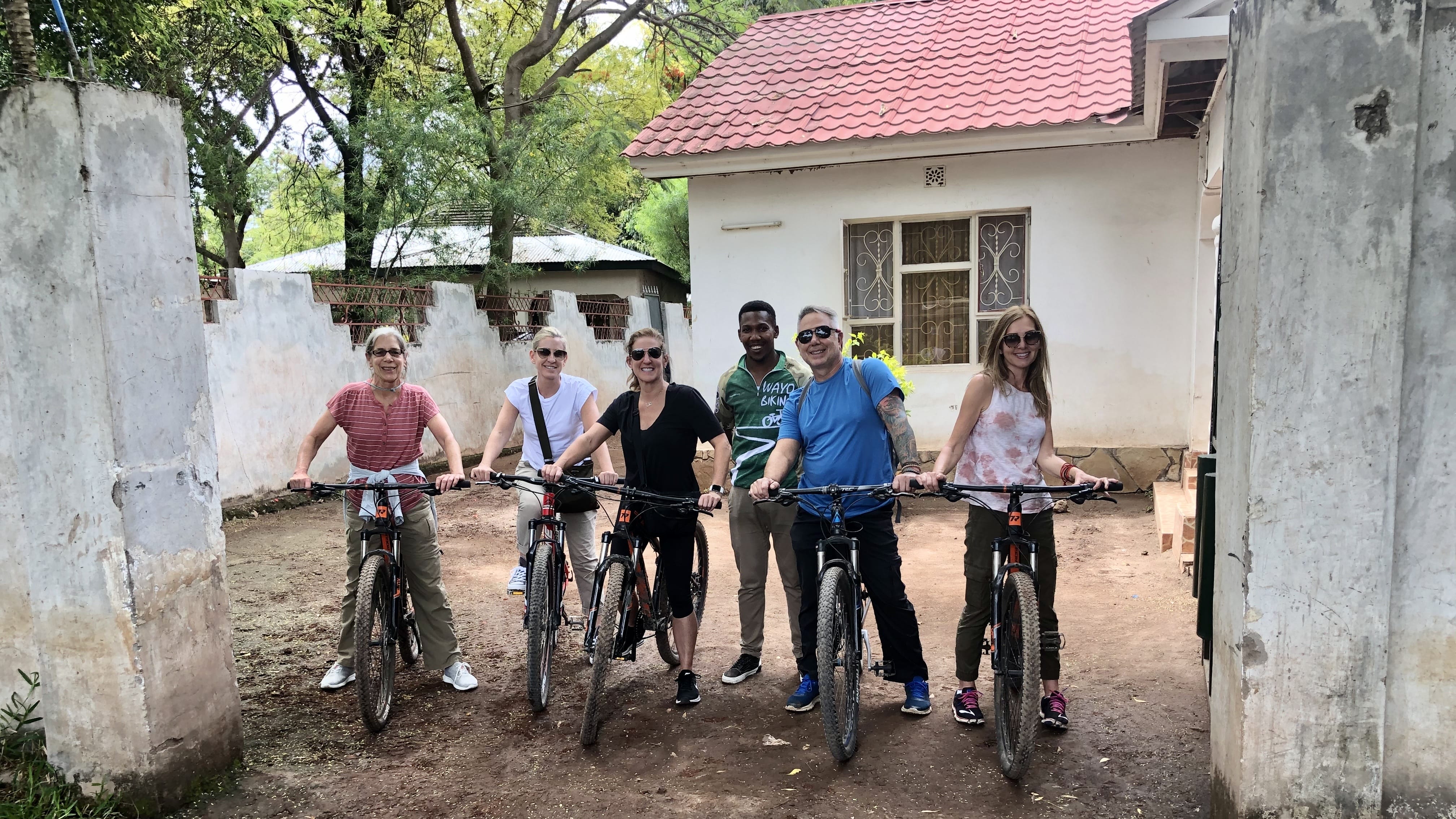 Small group posing with bicycles during a local village visit in Tanzania as part of a Tanzania safari itinerary.